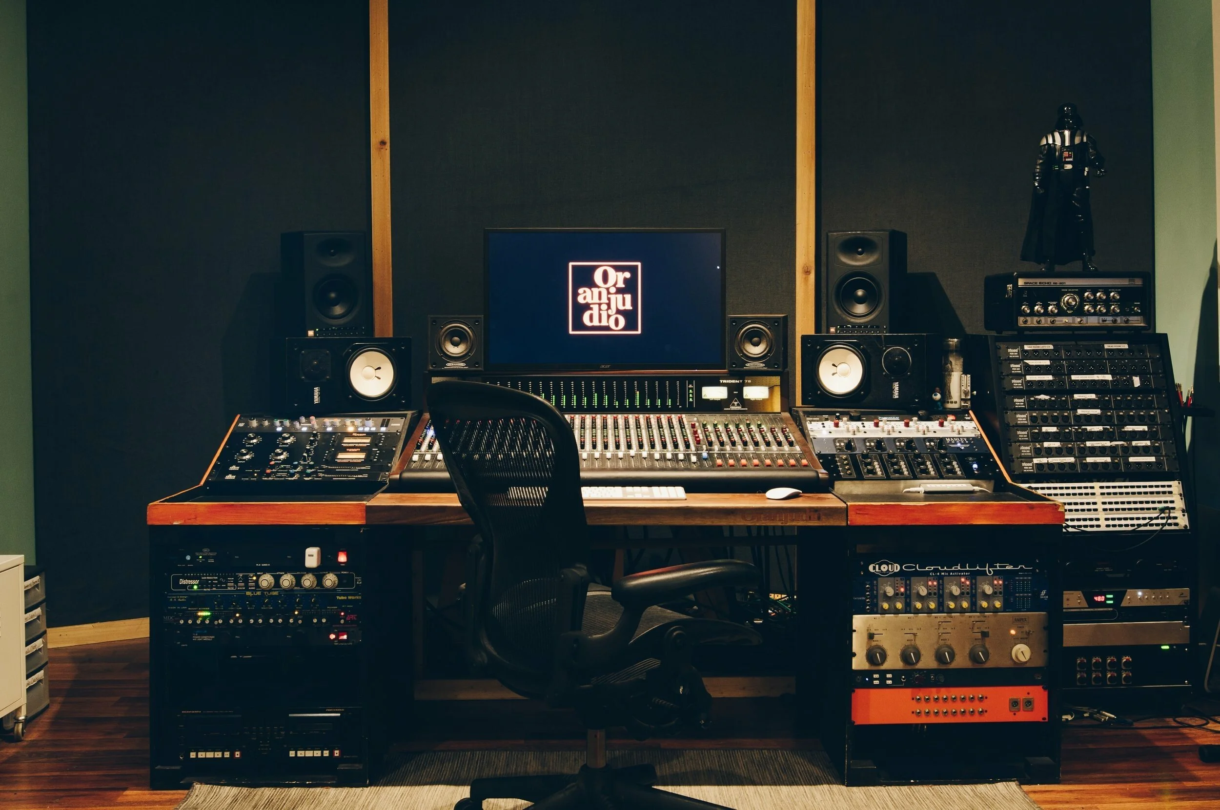 Music recording studio with a mixing console, studio monitors, audio equipment, and Star Wars Darth Vader figurine