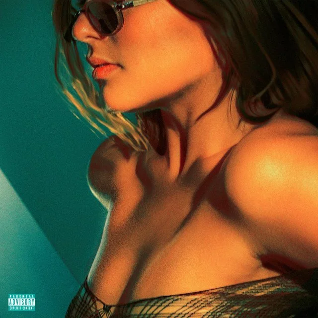 Close-up of a woman with long hair, wearing sunglasses, and a strapless top, with a colorful background.