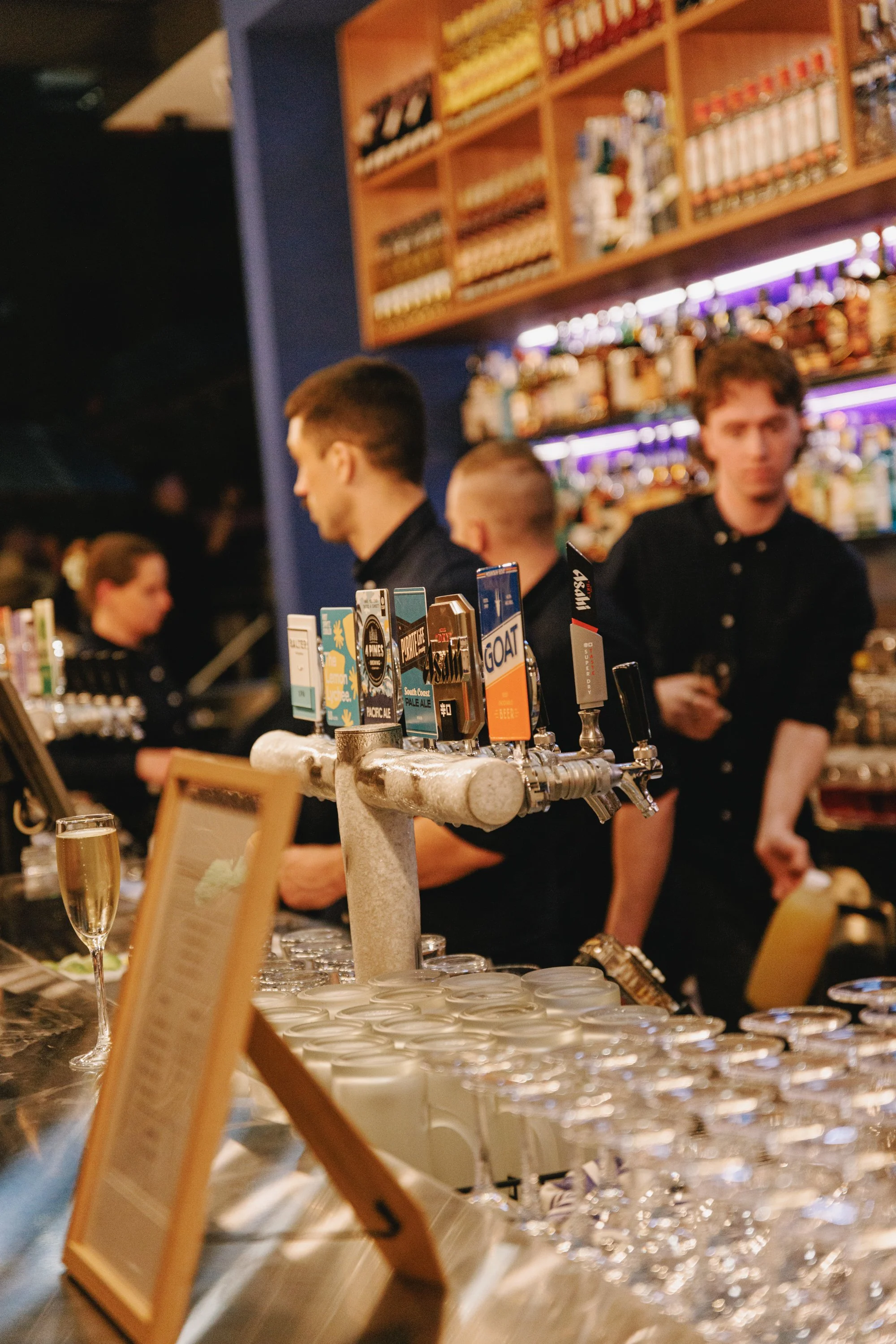 Bartenders pouring drinks behind the bar at Good Heavens Rooftop Bar on a busy night