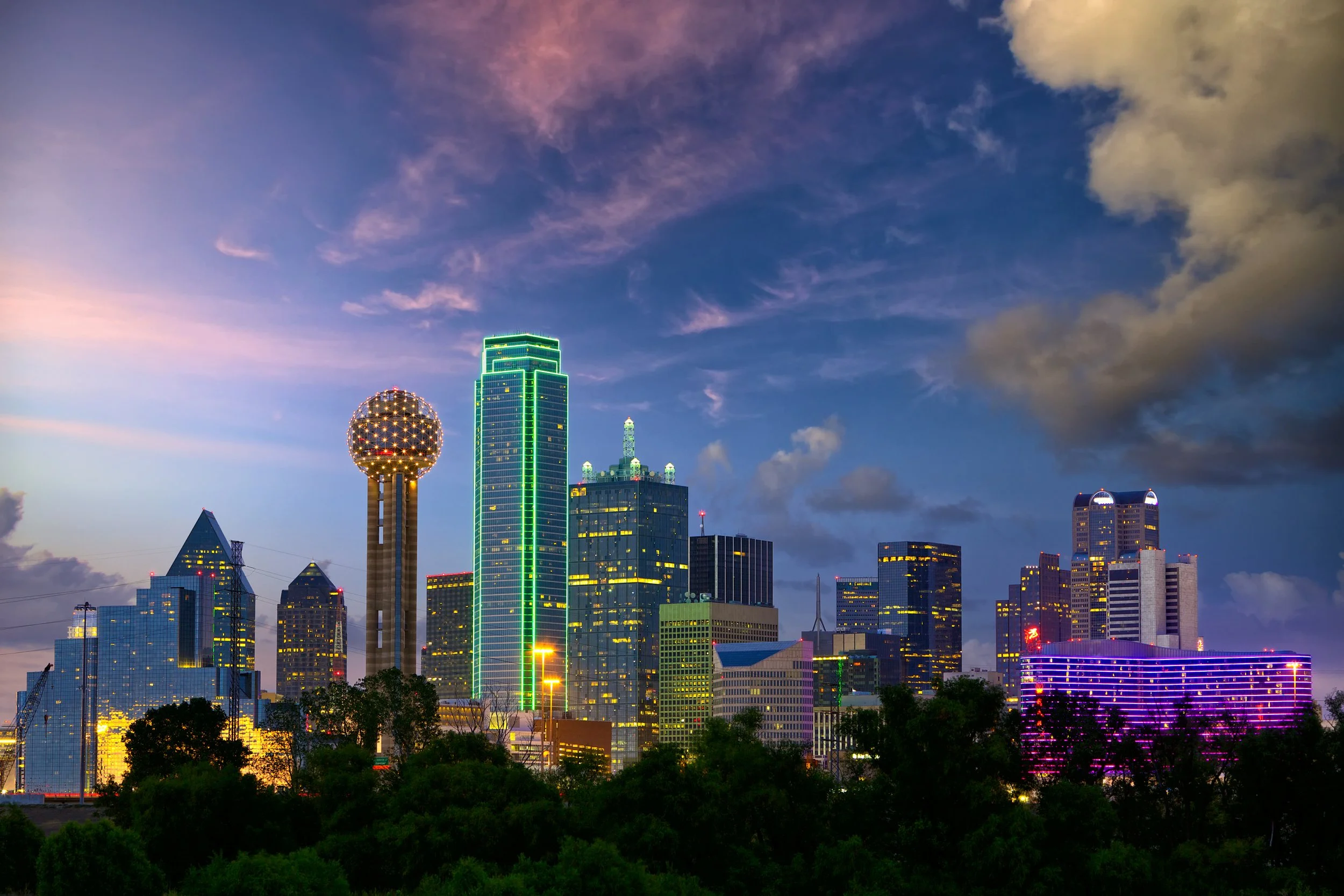 Dallas skyline at dusk with illuminated buildings and Reunion Tower.