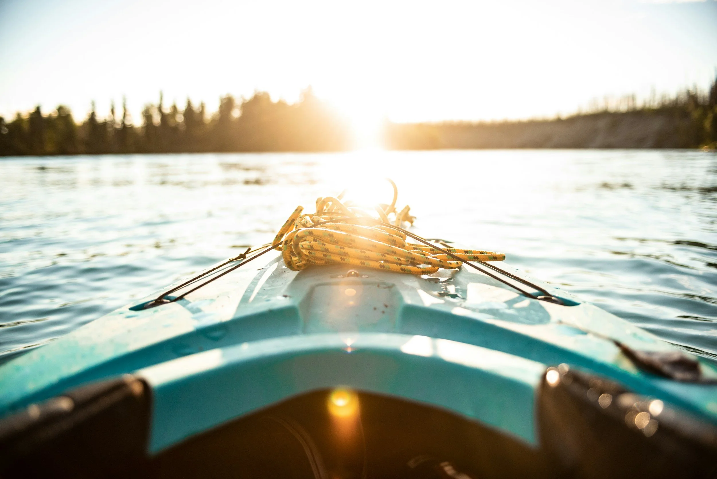 kayak on the lake pointing towards the shore with sunrise