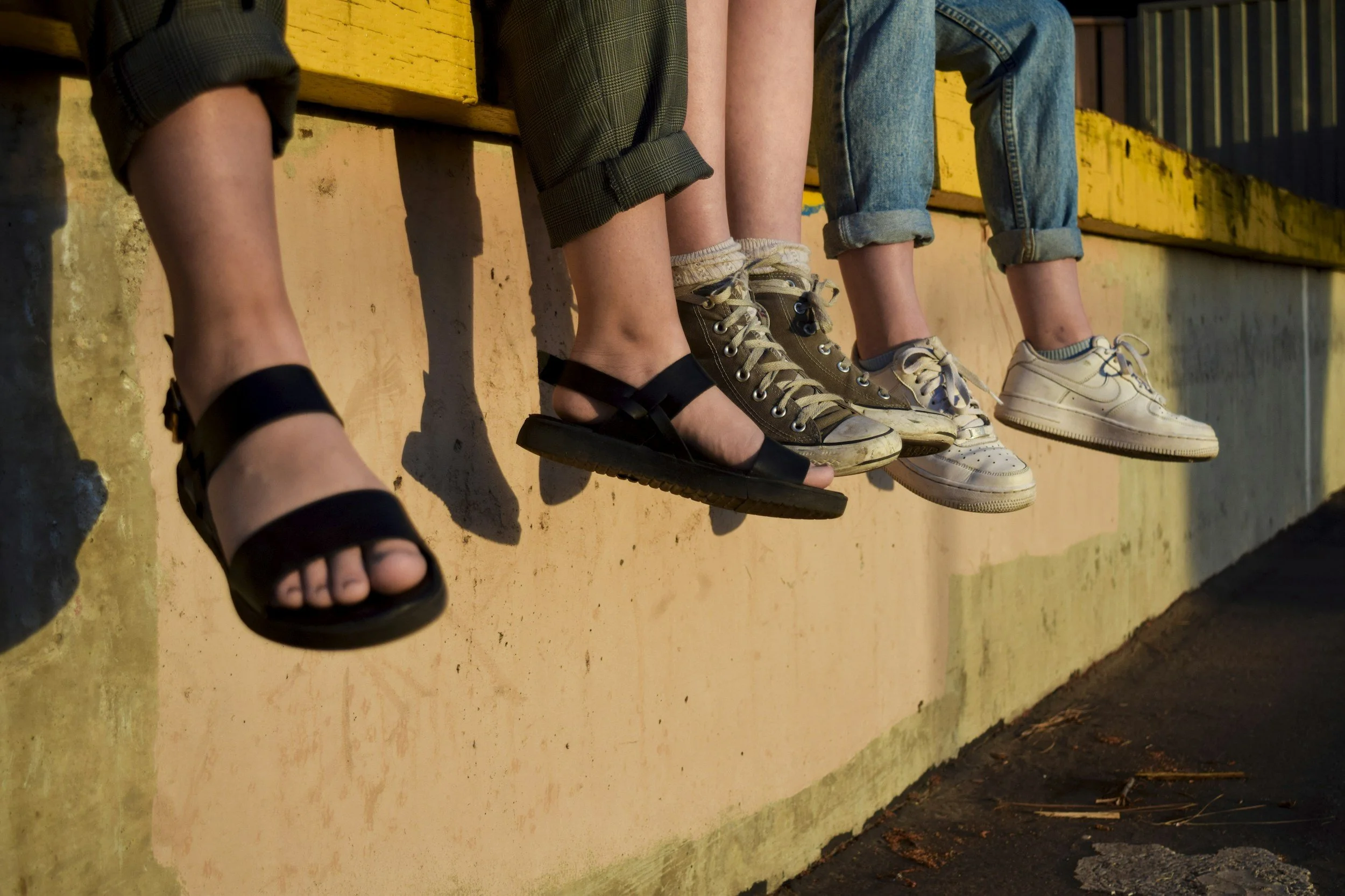 view of college students shoes and legs dangling while sitting