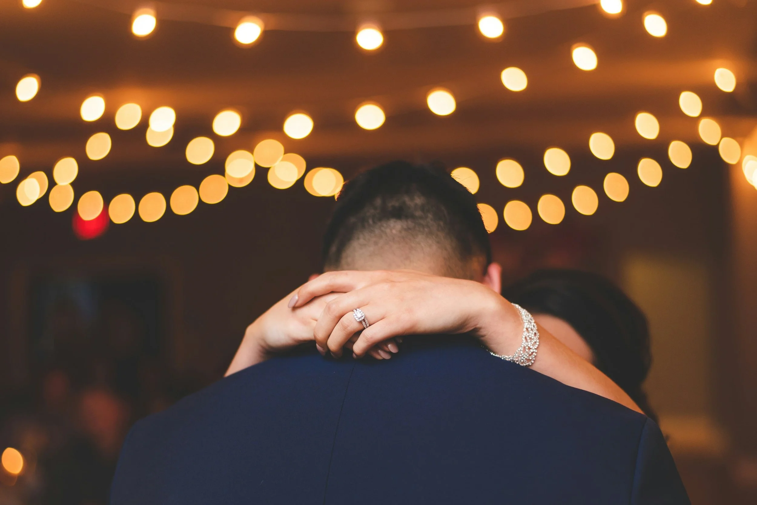 Close-up detail shot of a bride holding her groom with her wedding ring on display, representing the intimate aesthetic of Elyria Weddings.