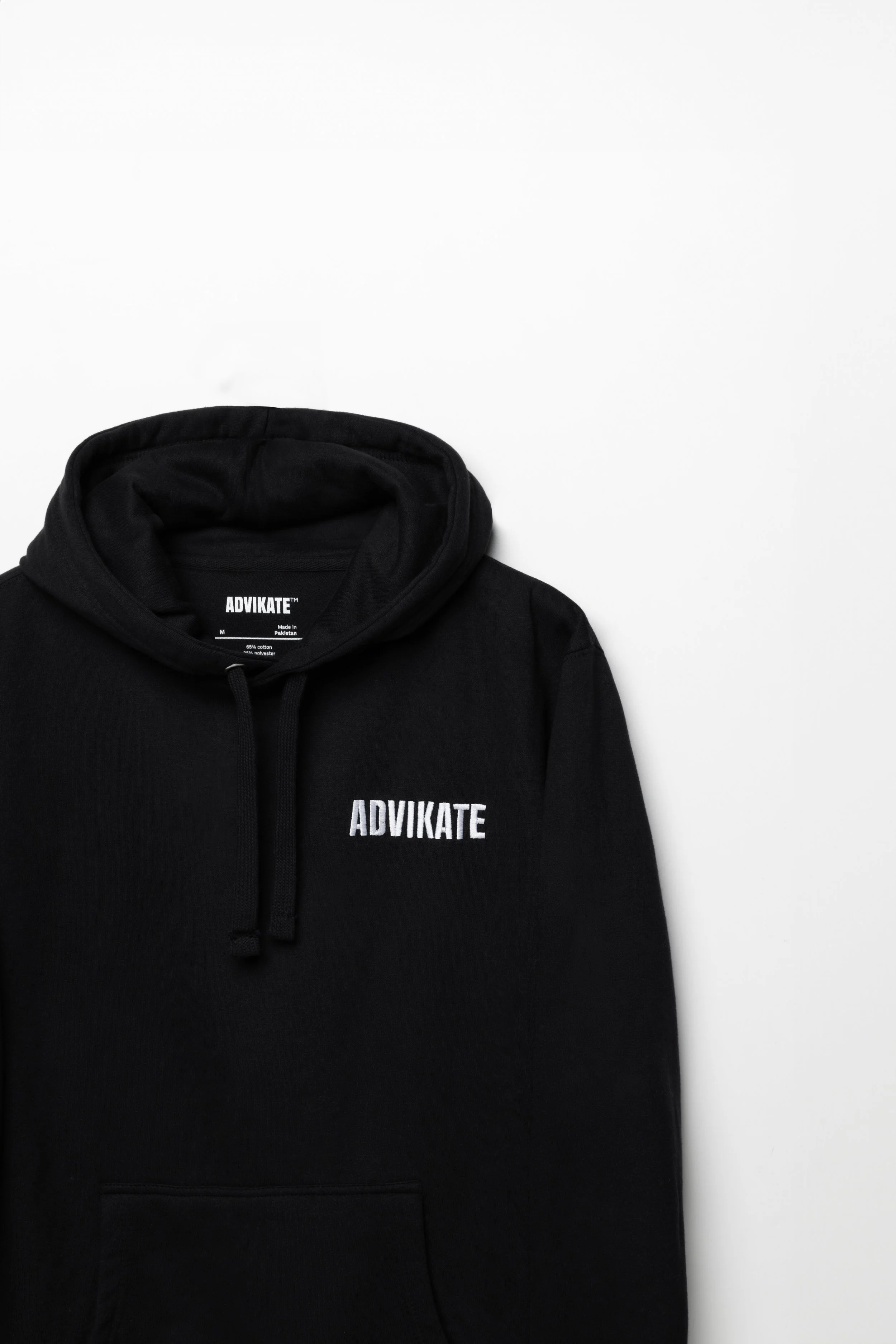 Close-up of ADVIKATE text embroidery on the chest of the ADVIKATE Classic Hoodie Series II in Black, showing stitch detail and texture.