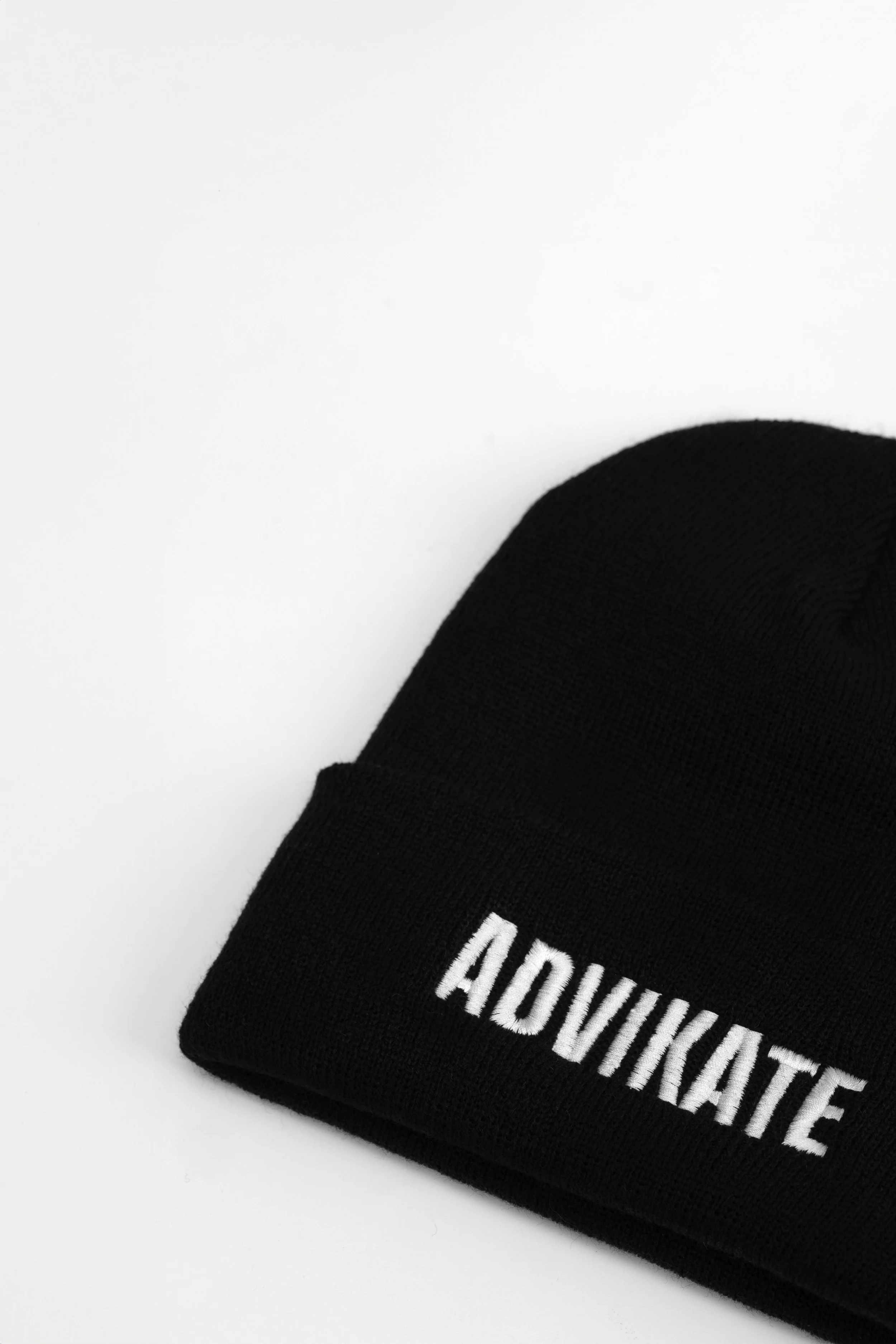Close-up of ADVIKATE text embroidery on the cuff of the ADVIKATE Classic Beanie Series II in Black, showing stitch detail and texture.