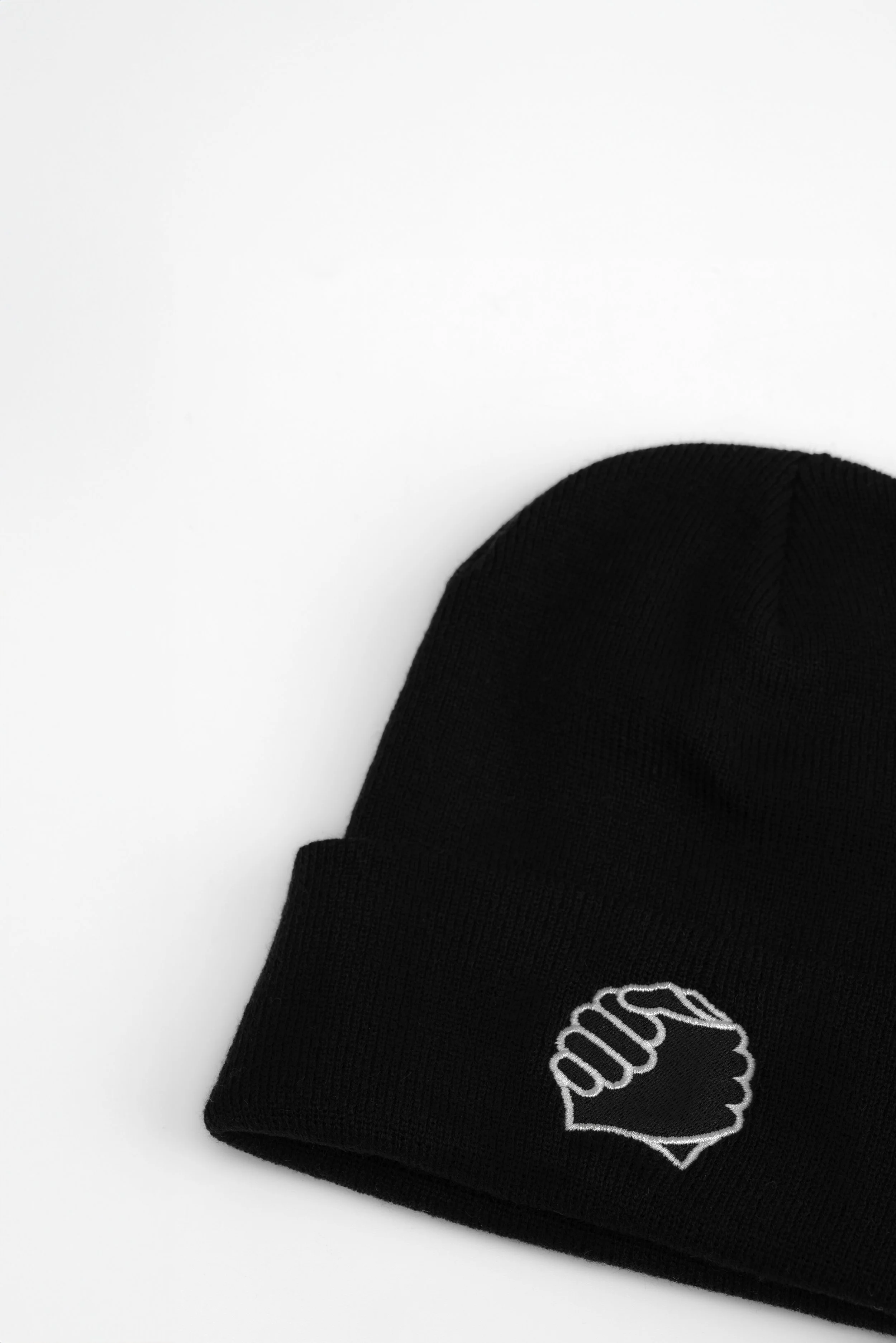 Close-up of clasped-hands embroidery on the cuff of the ADVIKATE Classic Beanie Series I in Black, showing stitch detail and texture.