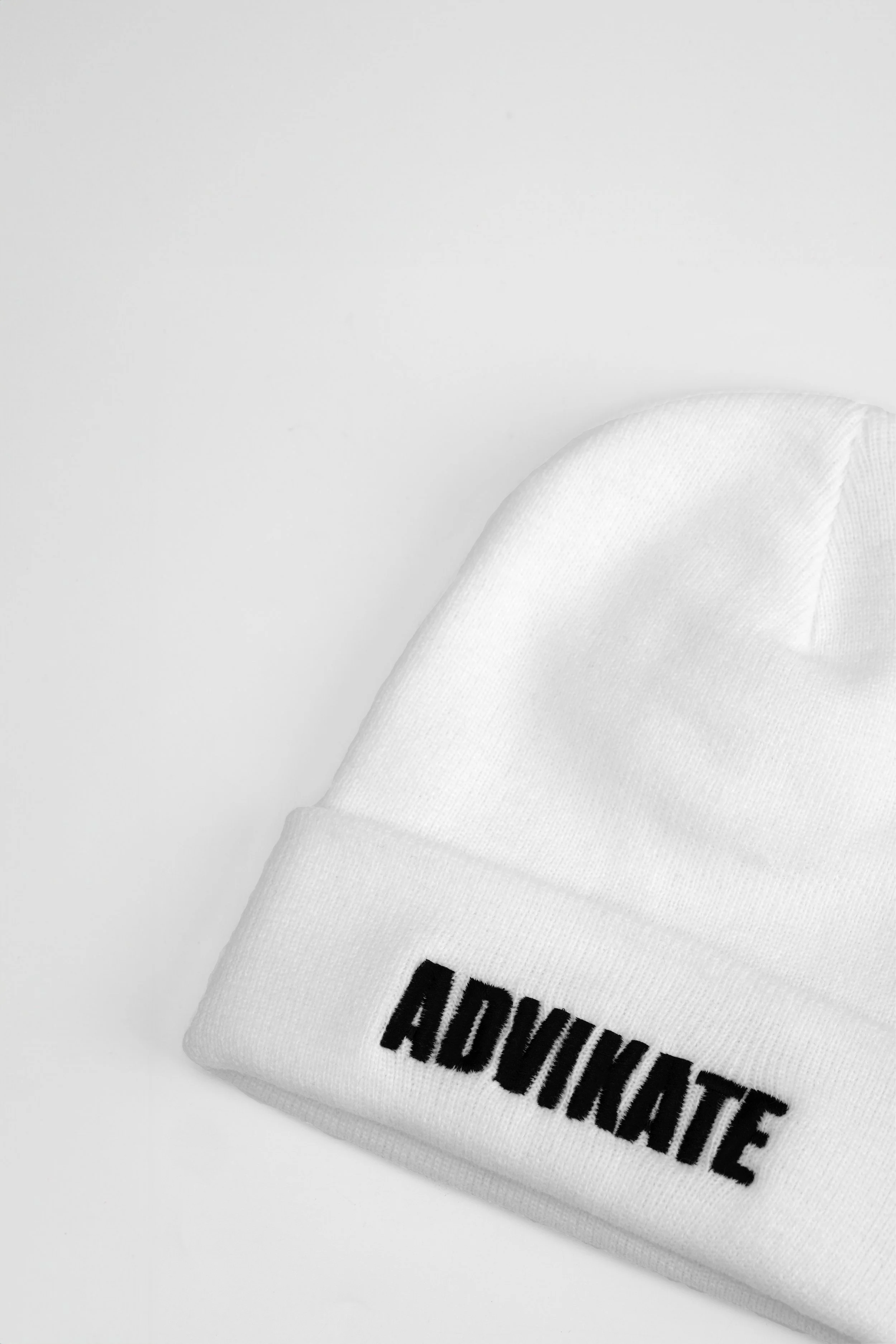 Close-up of ADVIKATE text embroidery on the cuff of the ADVIKATE Classic Beanie Series II in White, showing stitch detail and texture.