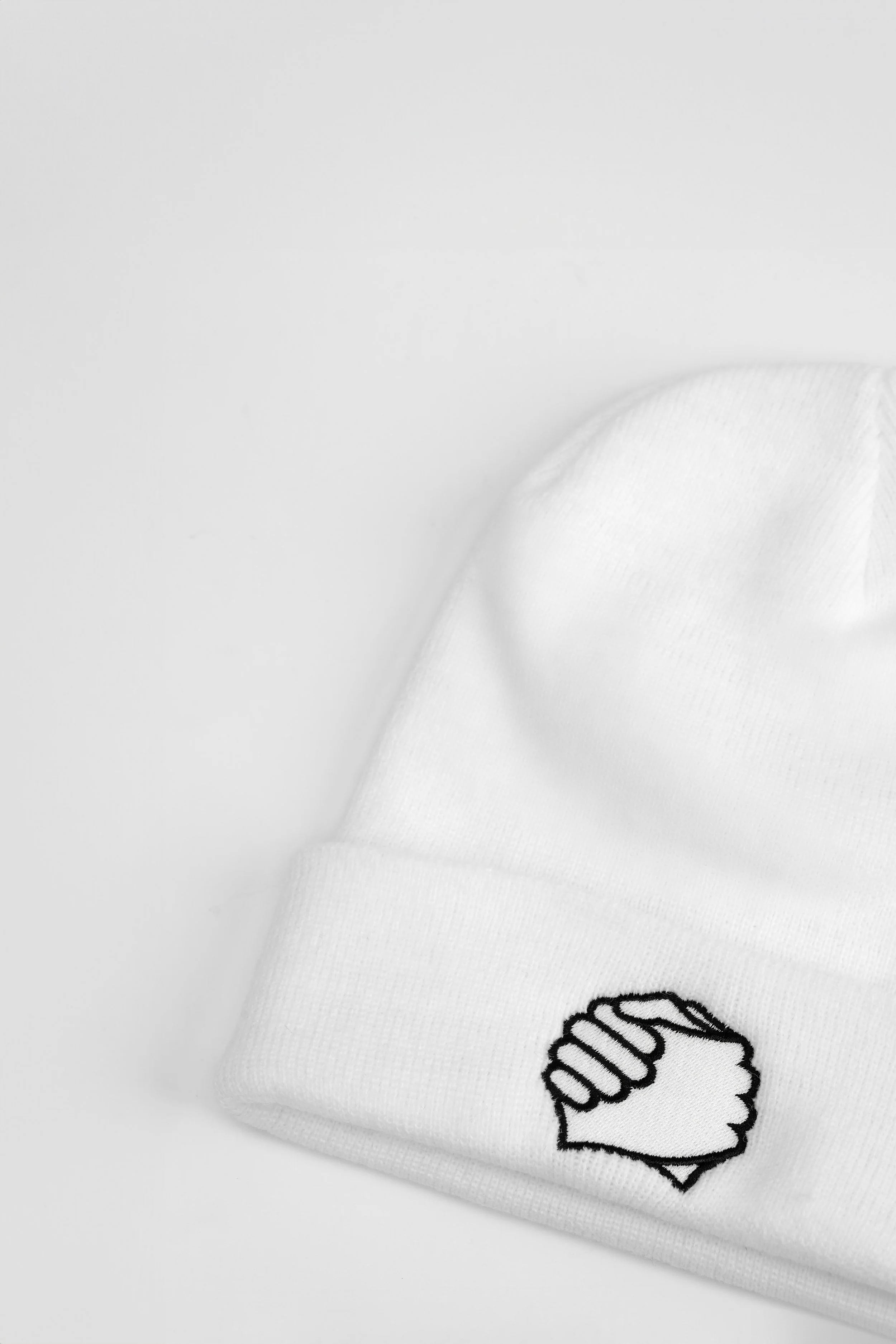 Close-up of clasped-hands embroidery on the cuff of the ADVIKATE Classic Beanie Series I in White, showing stitch detail and texture.