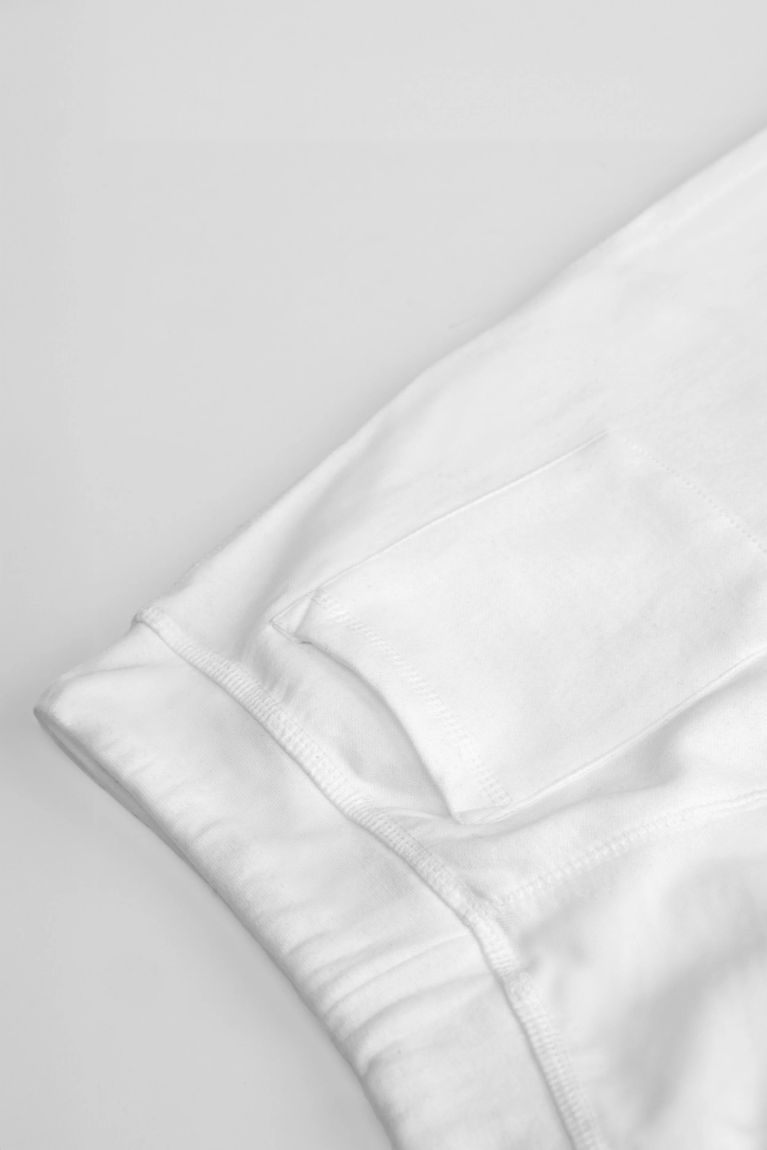 Close-up of the right back patch pocket on the ADVIKATE Classic Trackpants Series II in White, showing stitching and fabric detail.