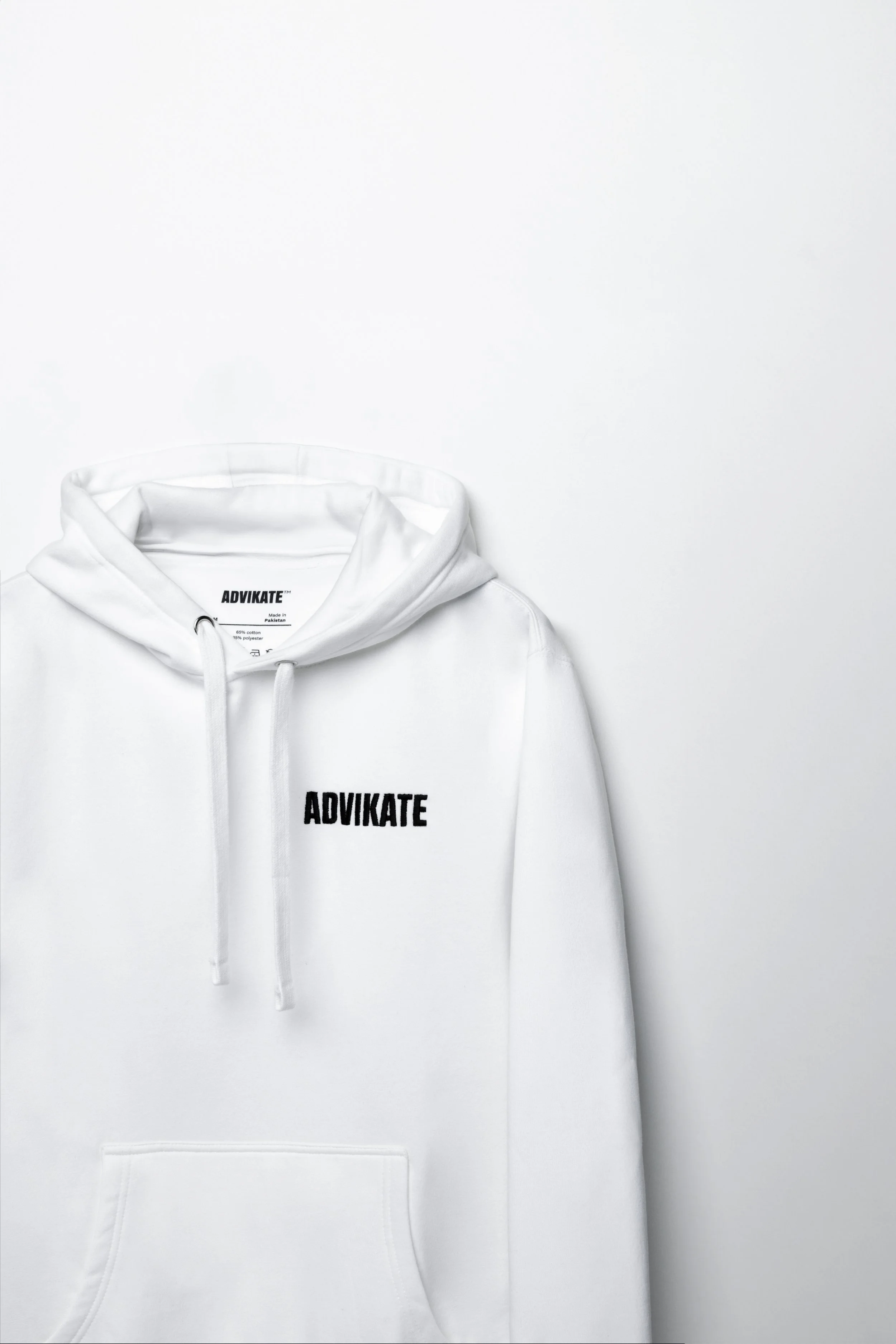 Close-up of ADVIKATE text embroidery on the chest of the ADVIKATE Classic Hoodie Series II in White, showing stitch detail and texture.