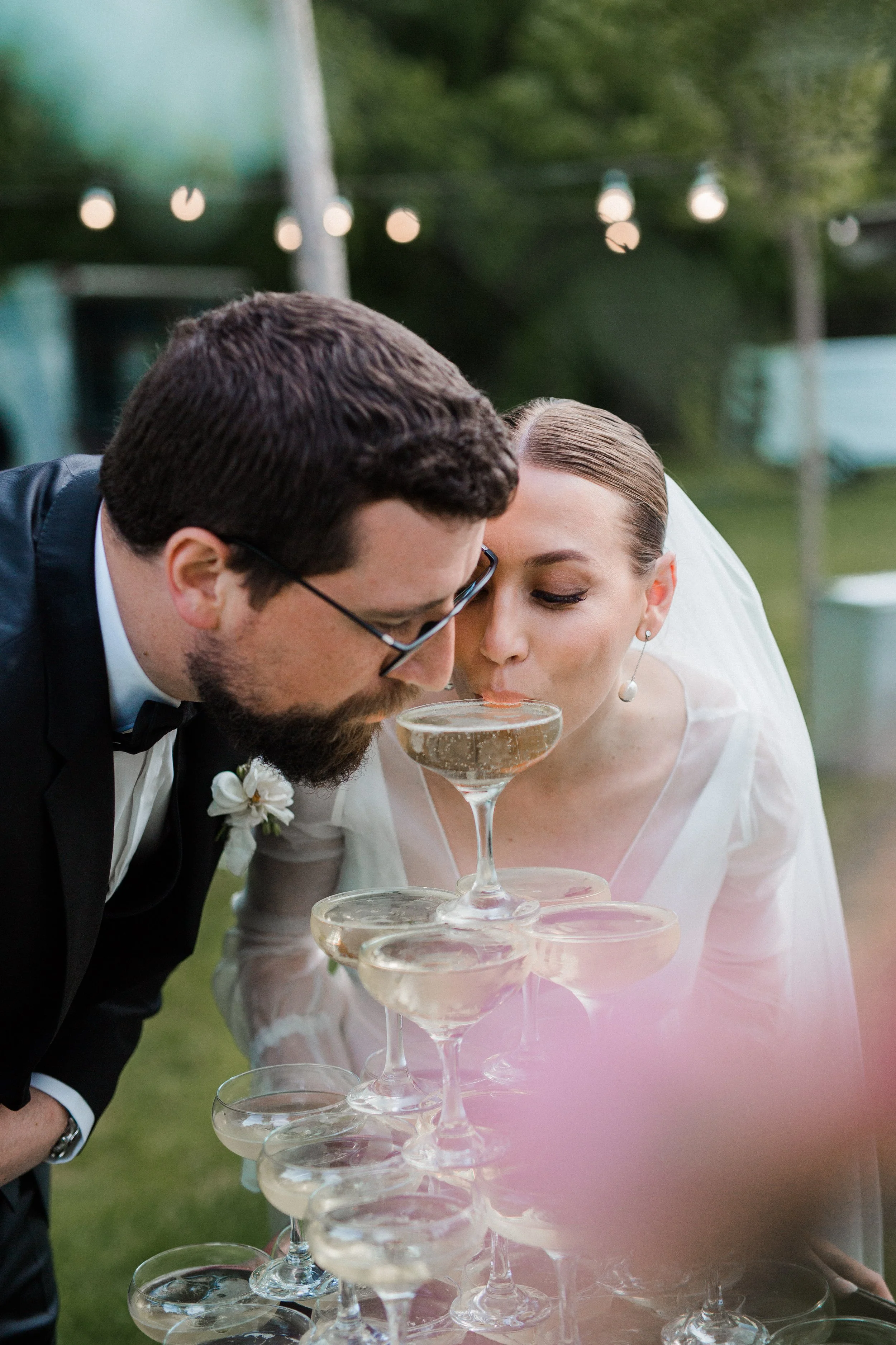 Bride and groom at wedding event drinking Champagne from a champagne tower