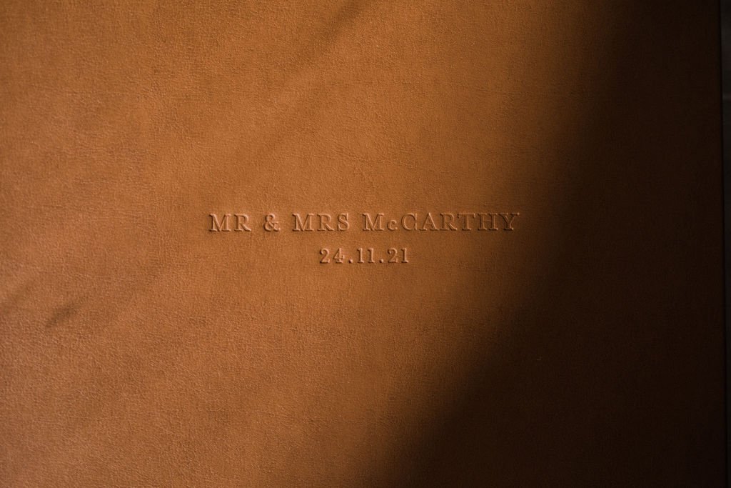 A close-up of a brown paper or cardboard material with embossed text that reads "MR & MRS McCARTHY 24.11.21".