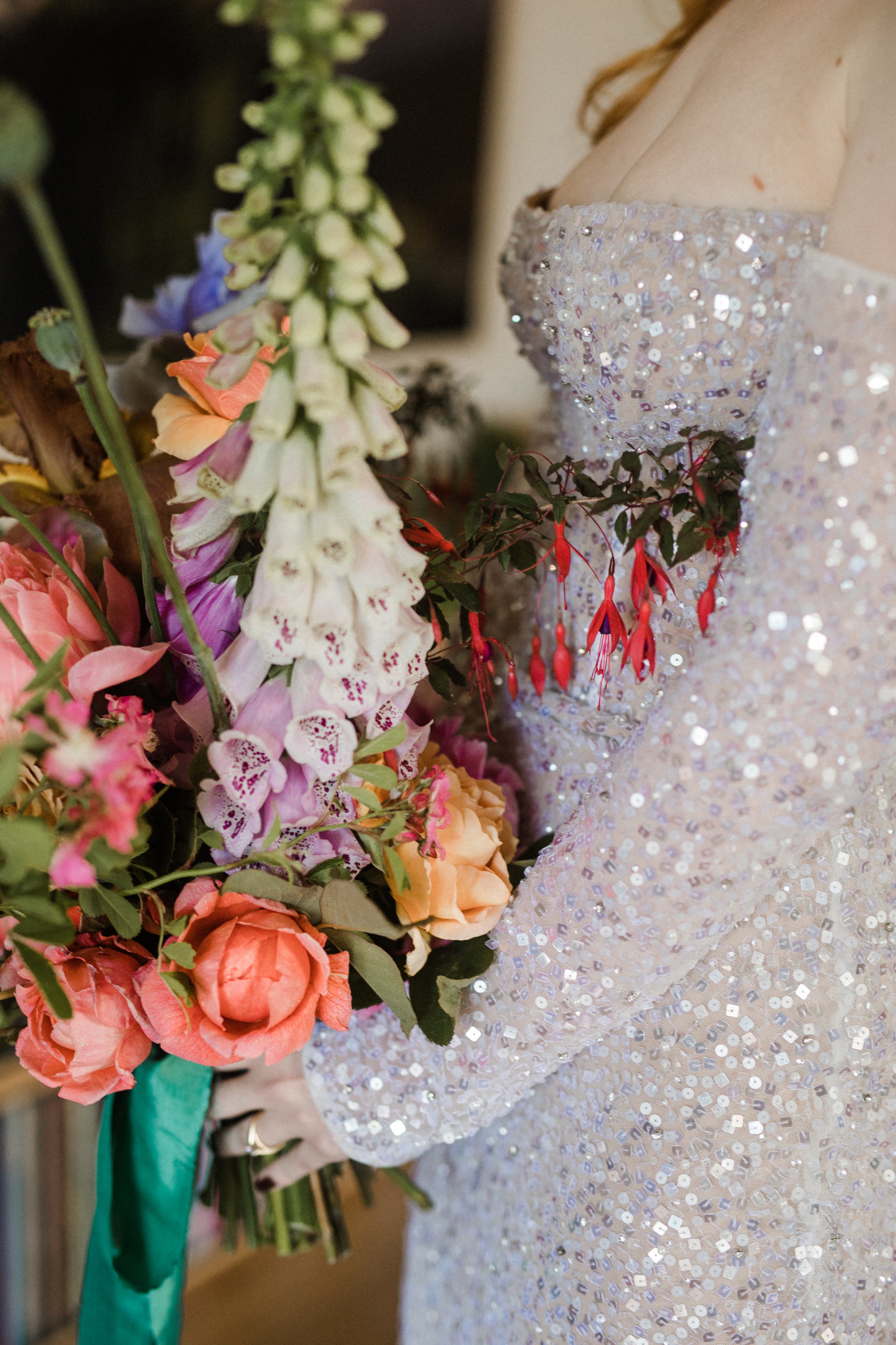 A woman in a sequin dress holding a large bouquet of colorful flowers.
