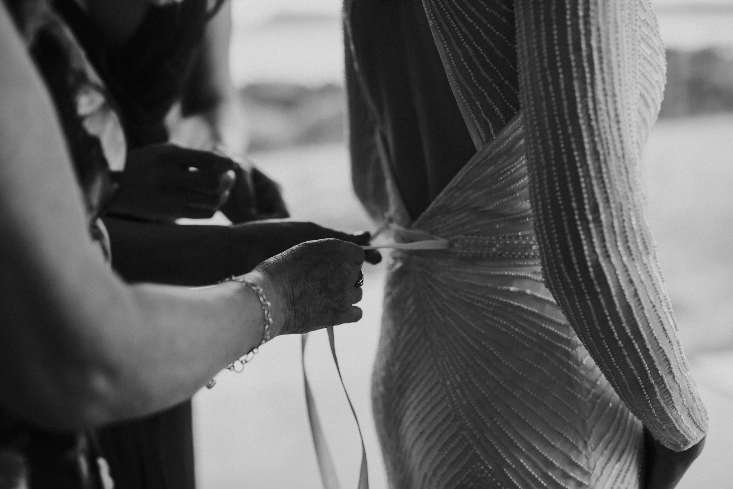 Close-up of hands adjusting the fabric of a wedding dress.