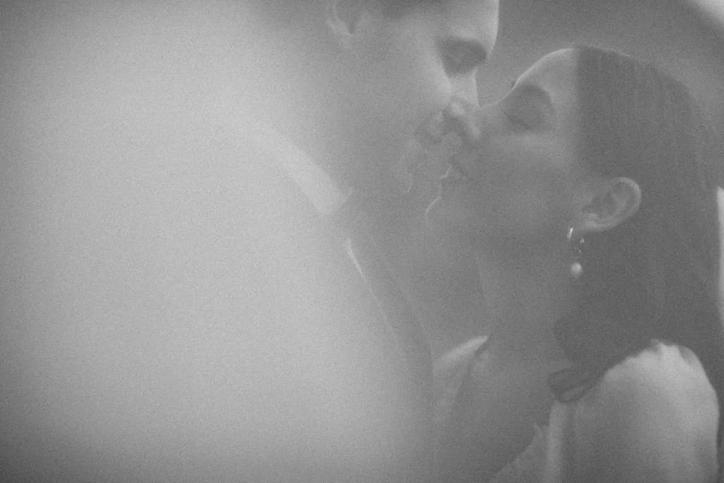 A black and white photo of a man and woman kissing, close-up view.