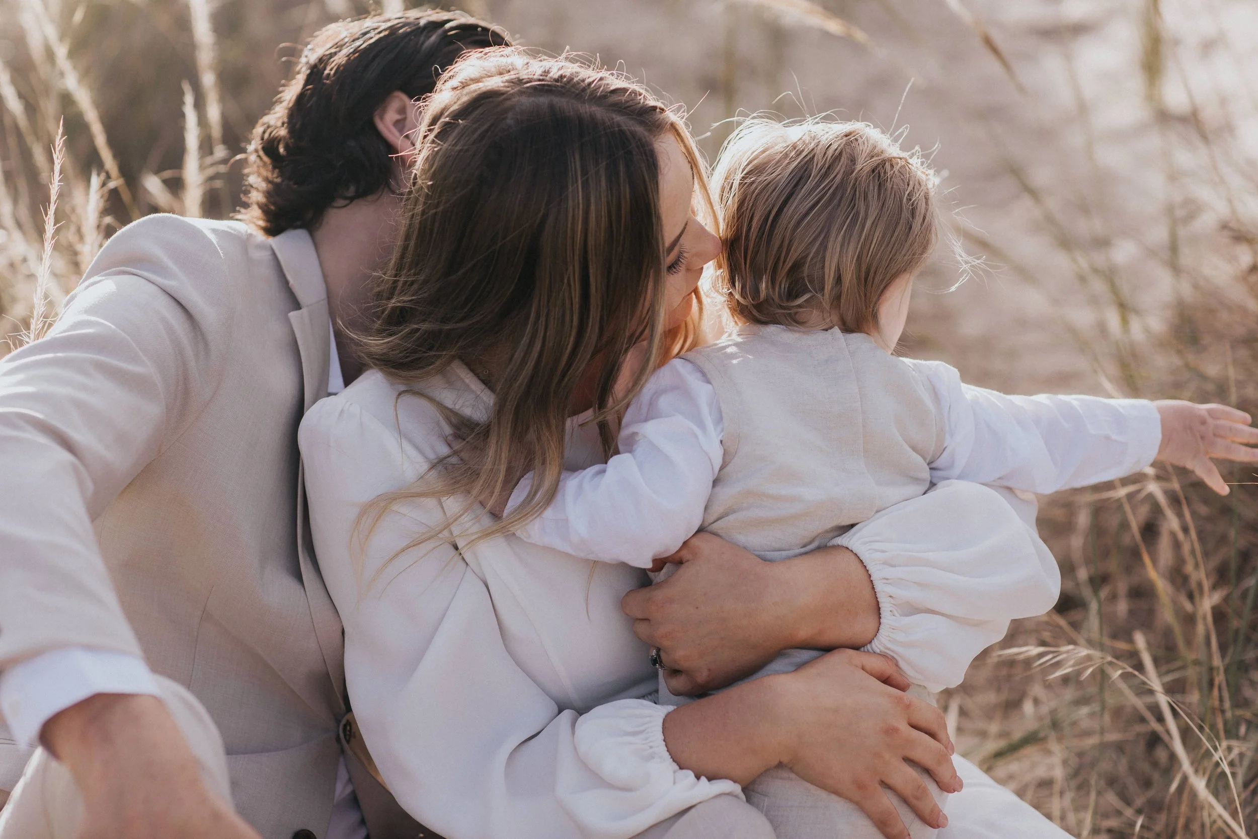 A woman and a girl looking and pointing at something in a grassy field.
