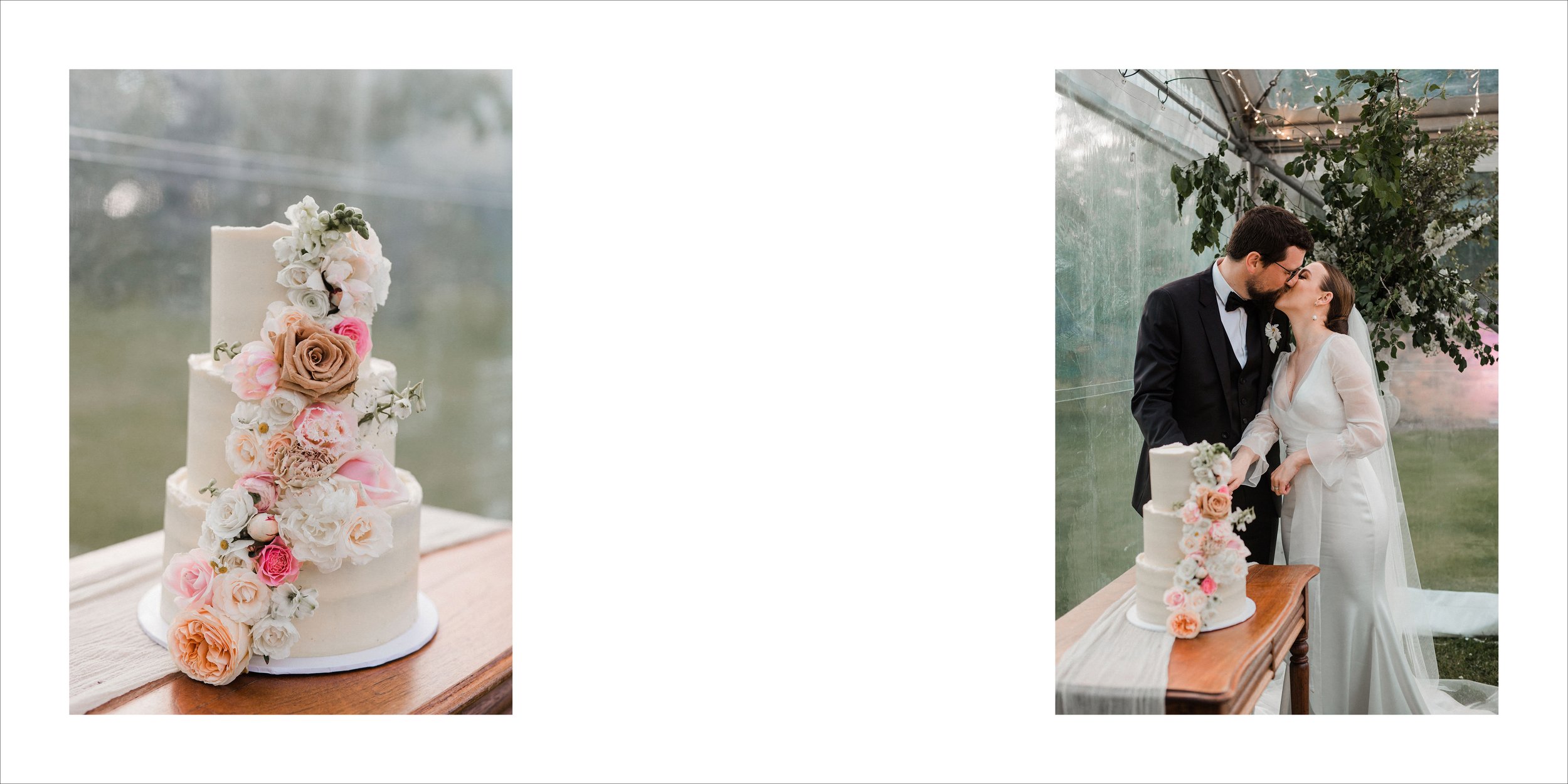 A wedding cake decorated with an arrangement of pink, white, peach, and beige flowers placed on a wooden table. In the background, a bride and groom are kissing in a glass-enclosed venue, with the bride wearing a white wedding dress and the groom in 