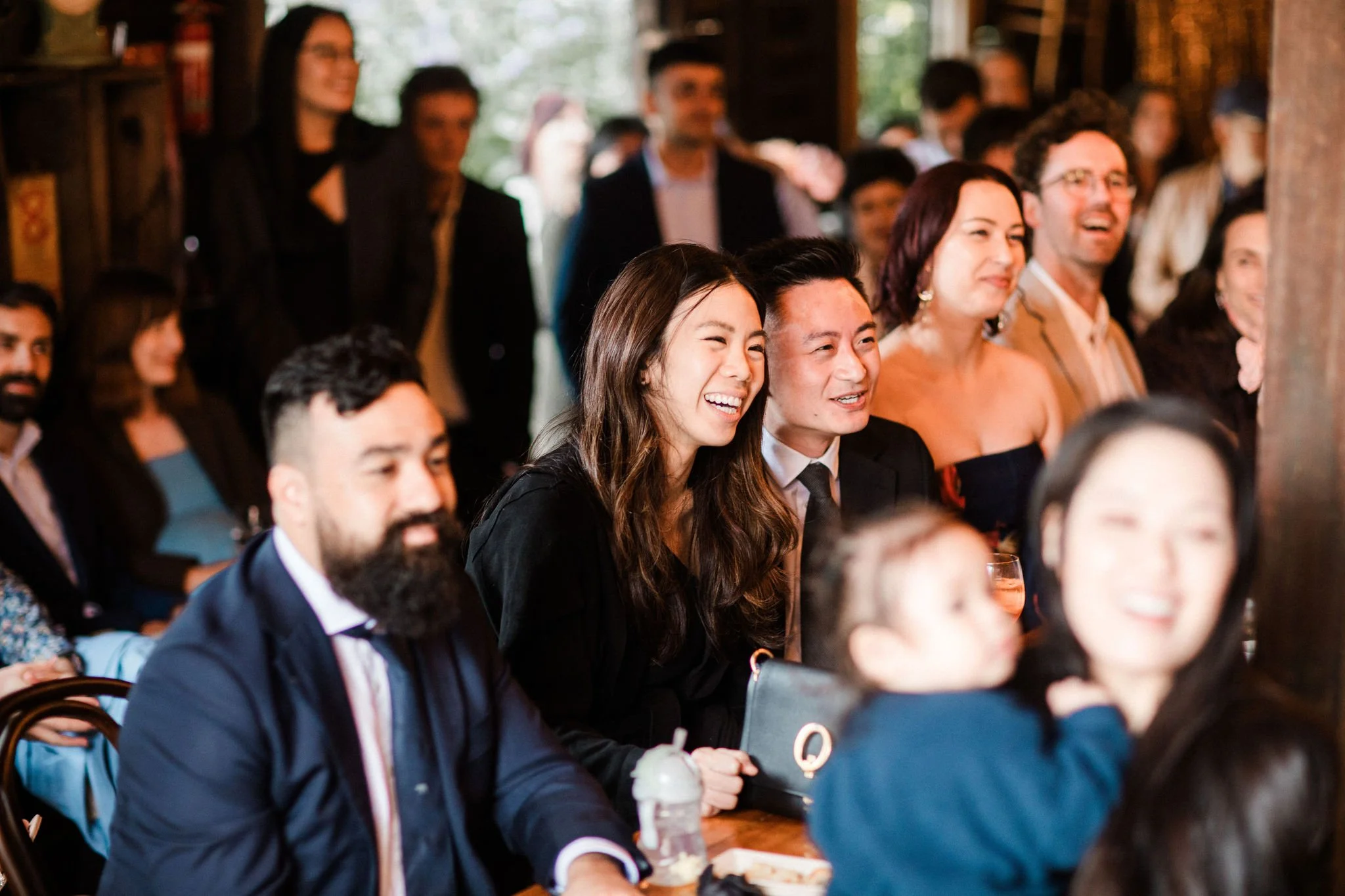 A group of people sitting at a table and laughing during a social event or celebration.