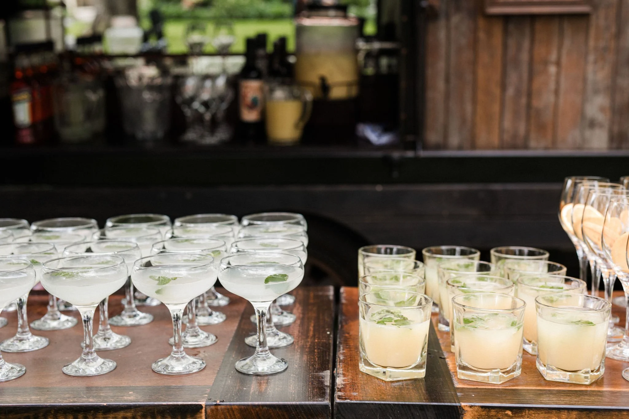 Assortment of cocktails served in cocktail glasses and short tumblers, garnished with lime slices, on a wooden table.