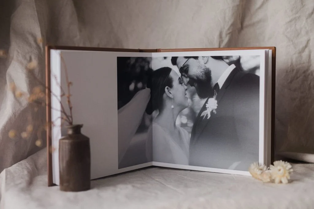 Open wedding photo album displaying a black and white photo of a bride and groom facing each other closely.