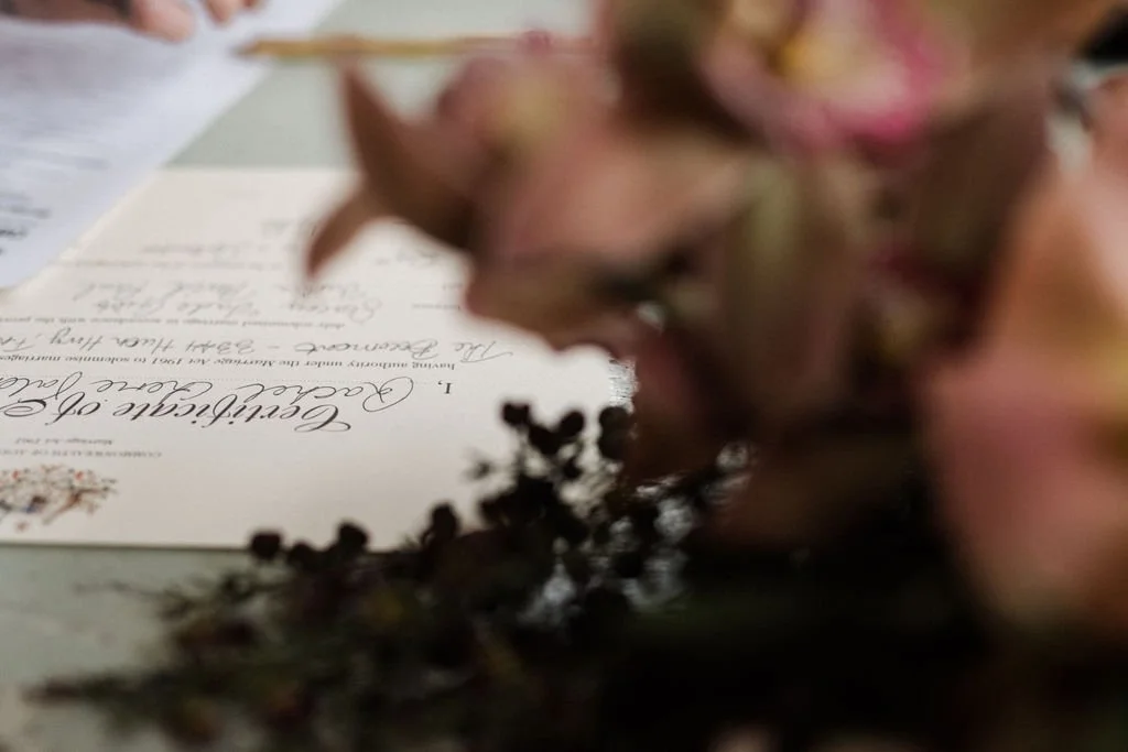 Close-up of a wedding certificate with a bouquet of flowers in the foreground.