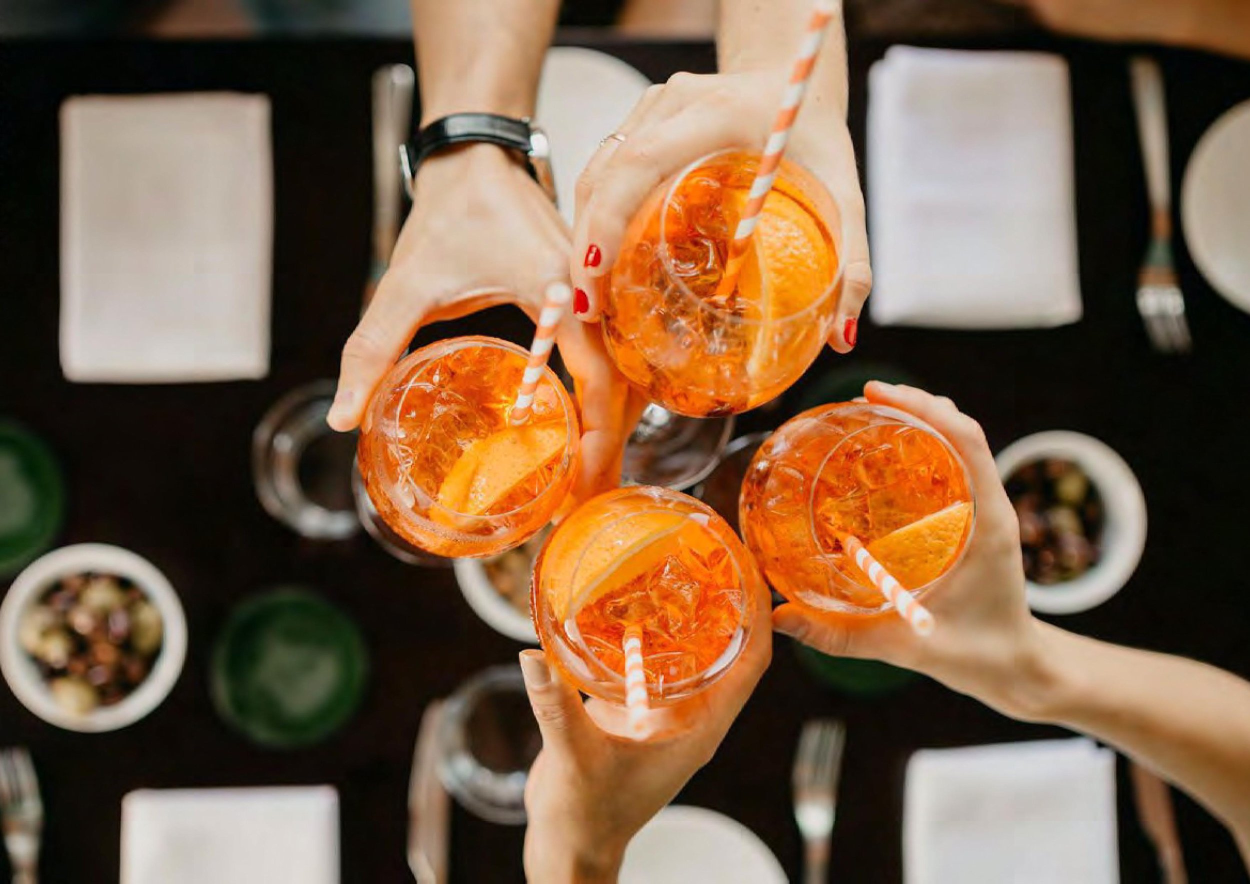 People cheering with aperol spritzs in hand