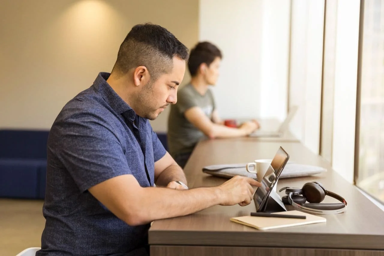 man-sitting-on-white-chair-pointing-on-tablet-screen-inside-room