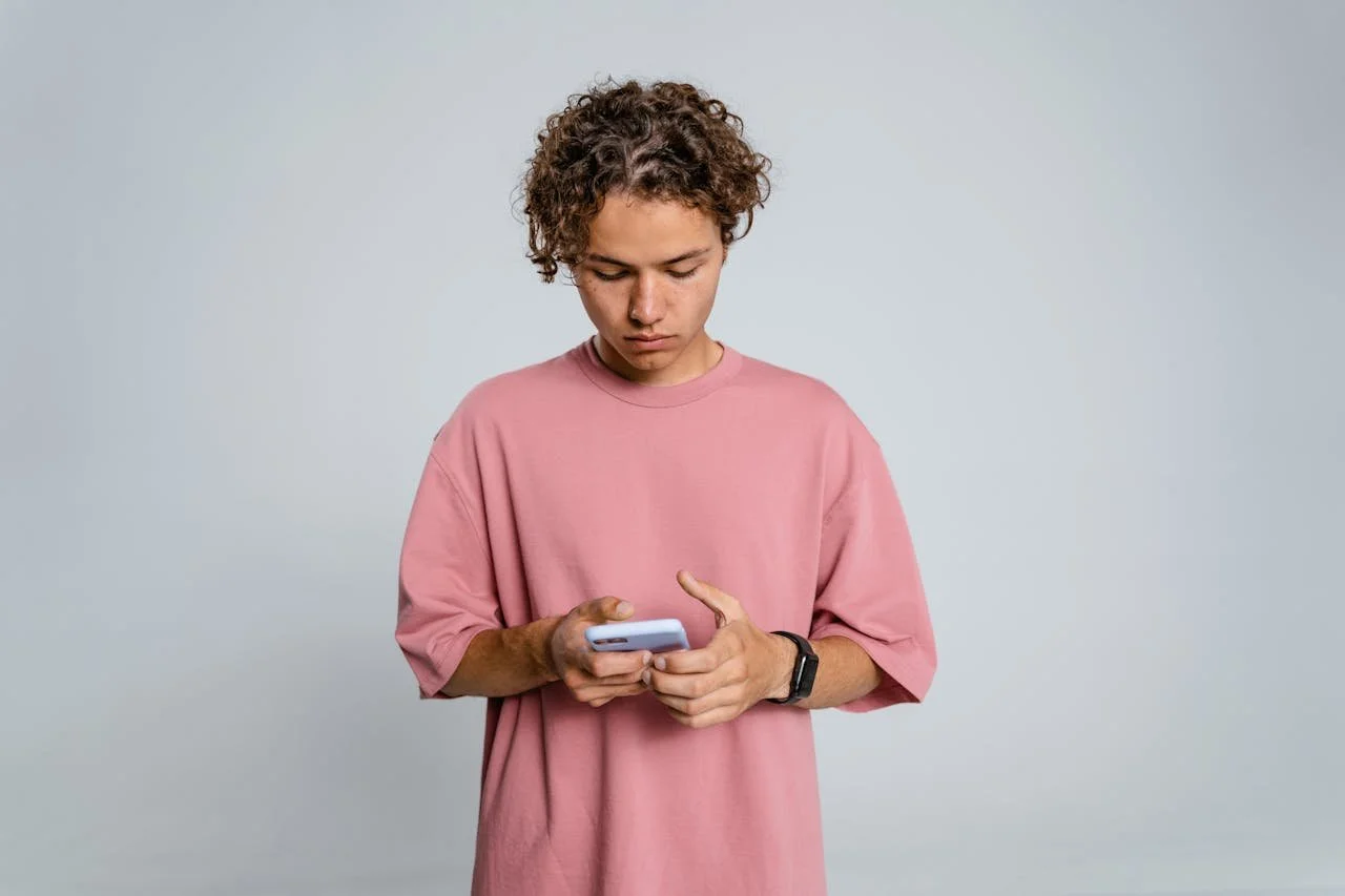 teen-in-pink-crew-neck-long-sleeve-shirt-holding-black-smartphon