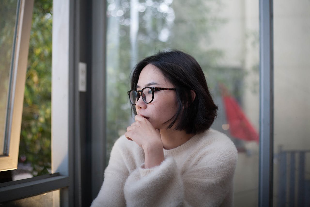 a-woman-in-a-white-sweater-sitting-by-a-window