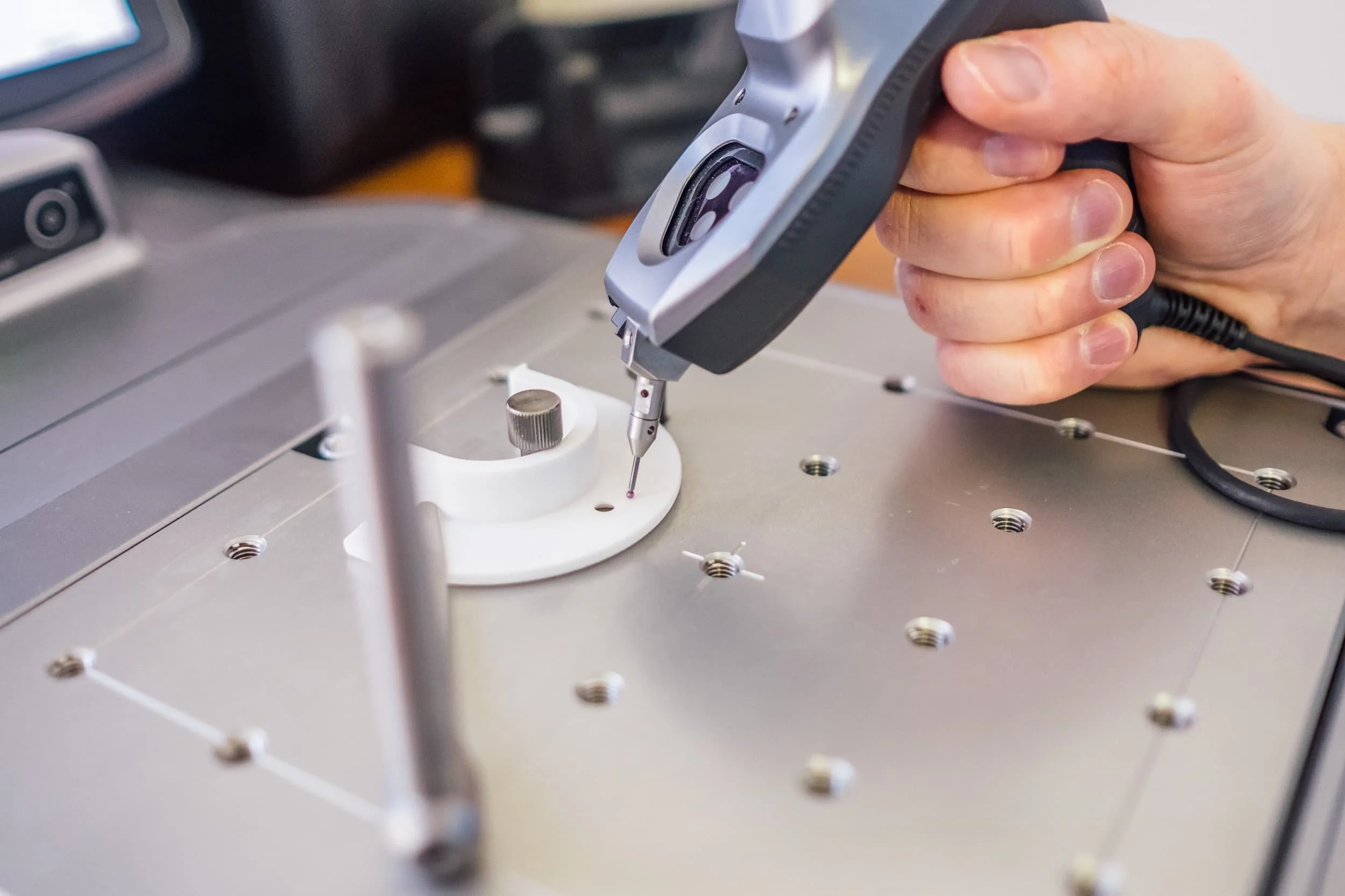 Hand hält ein Messgerät über eine elektronische Platine auf einer Leiterplatte.