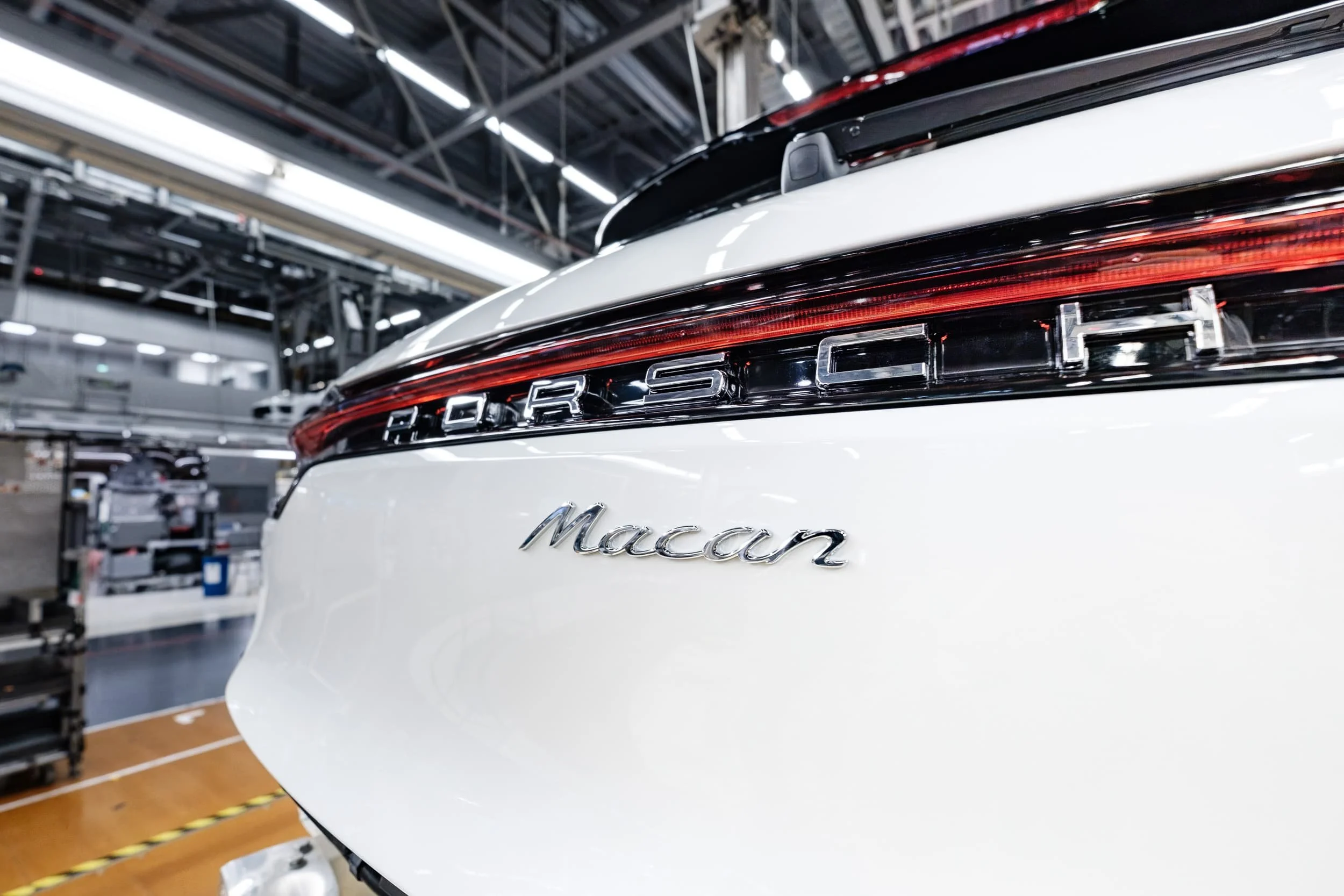 Der hintere Teil eines weißen Mercedes-Benz Autos mit dem Emblem und dem Schriftzug "Maran" auf der Rückseite, in einer modernen Fabrikhalle.