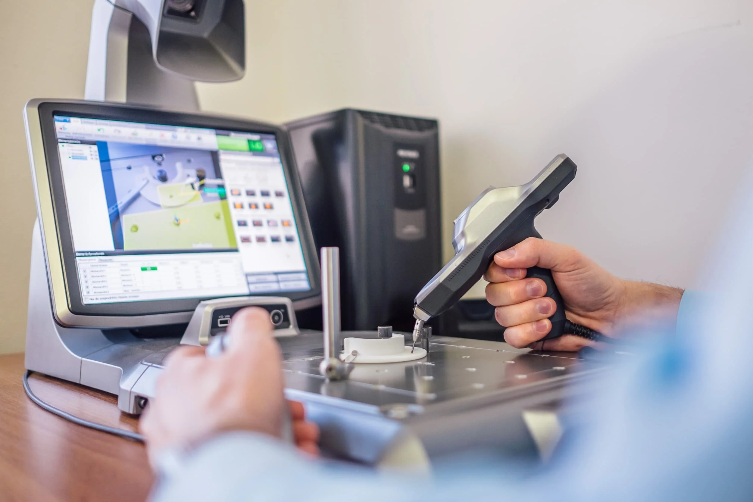 Hand hält ein elektronisches Messgerät bei einer Laborarbeit an einer weißen Substanz auf einem Laborgerät, Bildschirm zeigt eine Software mit Messdaten.