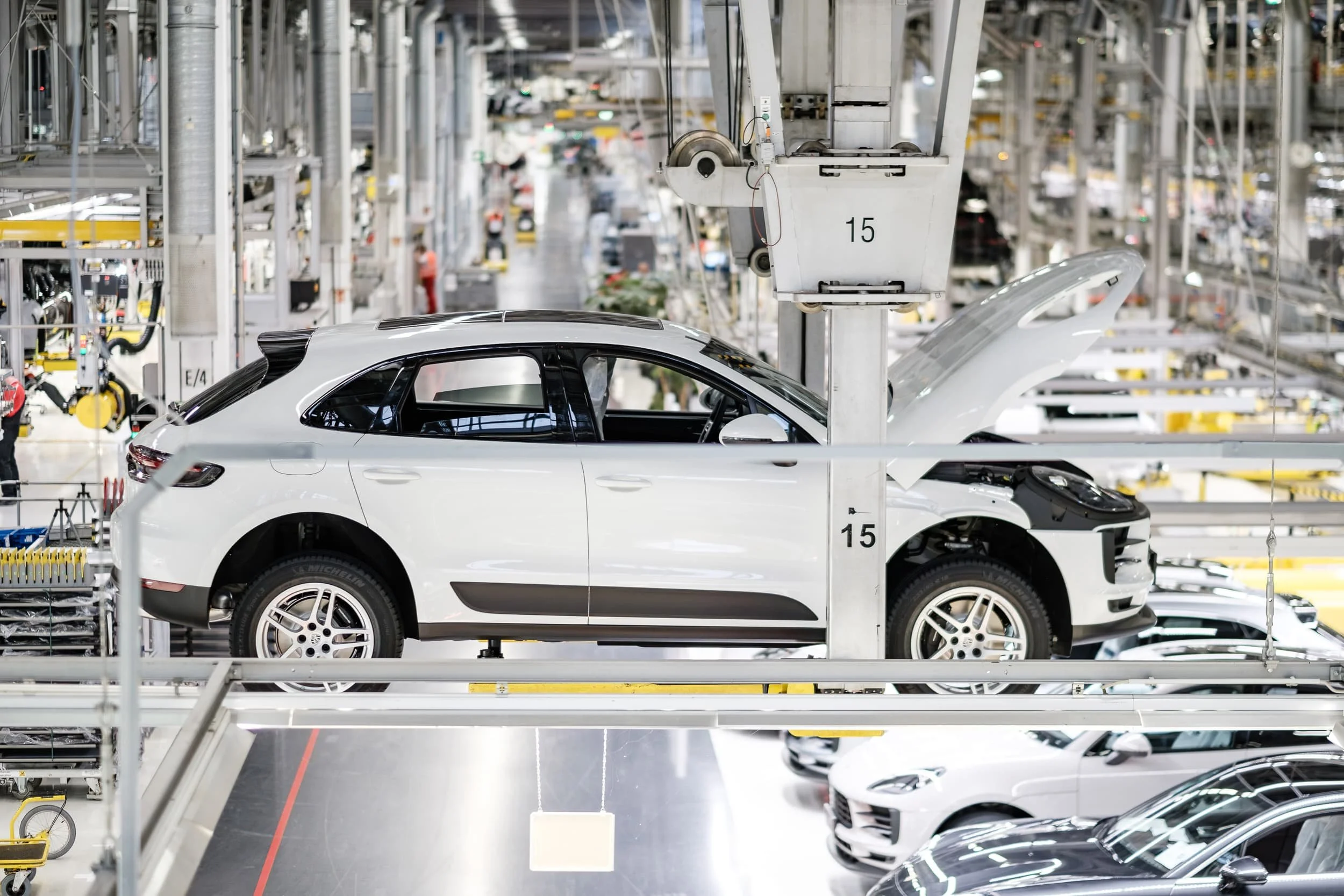 Innenansicht einer Autoproduktionshalle mit weißen Autos auf Montagelinien.