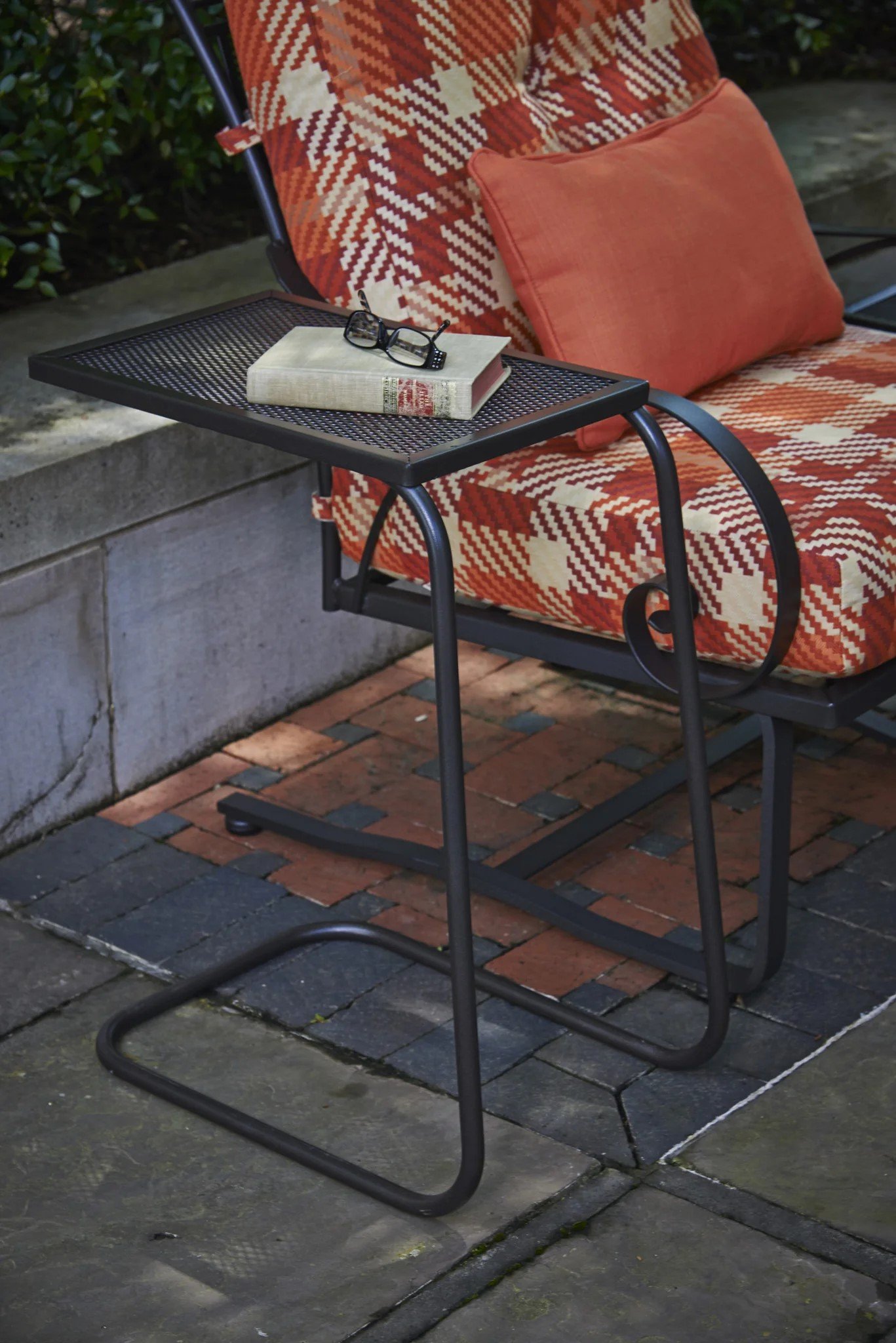 wrought iron end table next to red plaid cushioned chair 