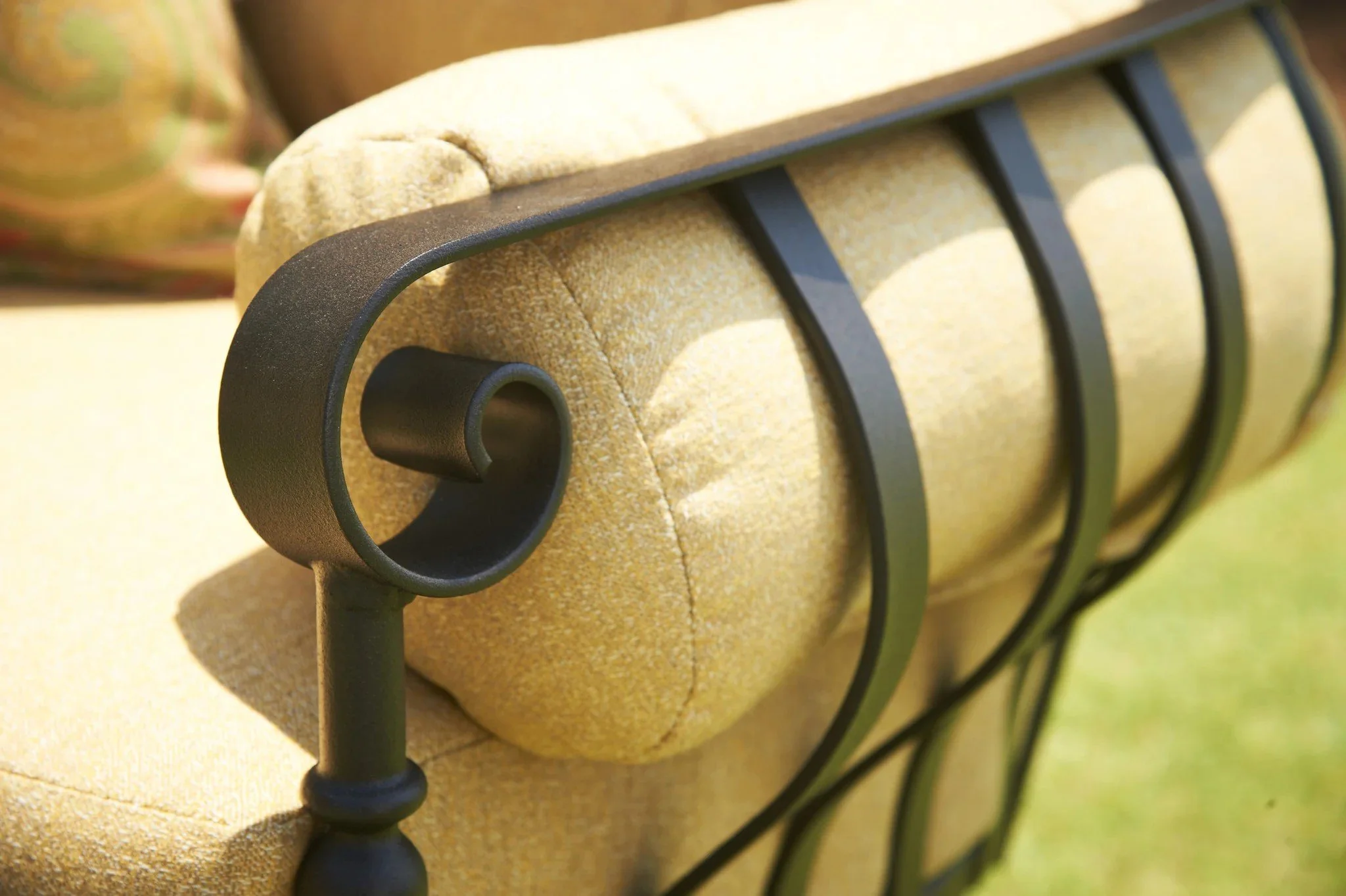 close up of wrought iron chair arm and yellow cushion