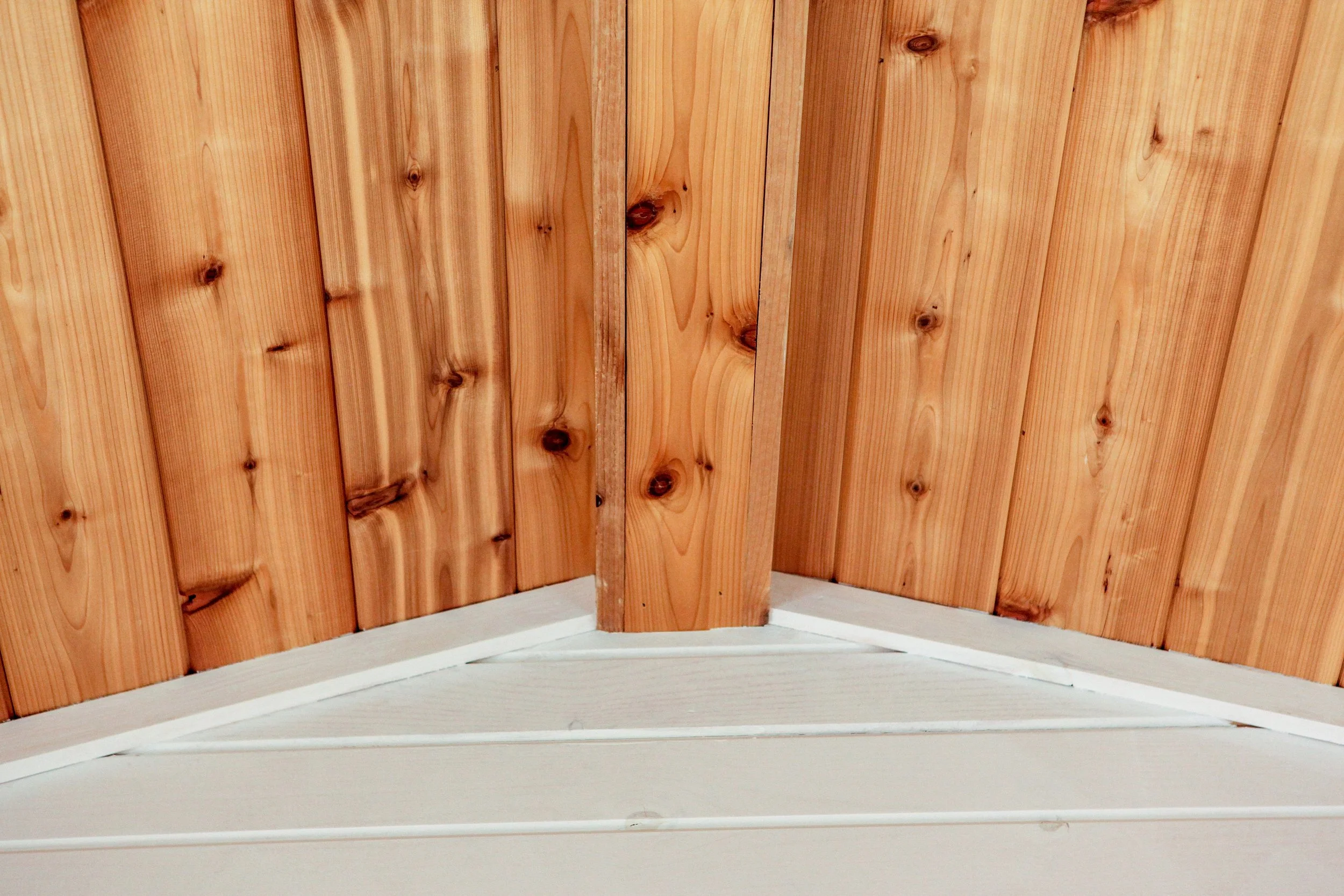 Ceiling made of wooden panels with visible nails and a central wooden beam.