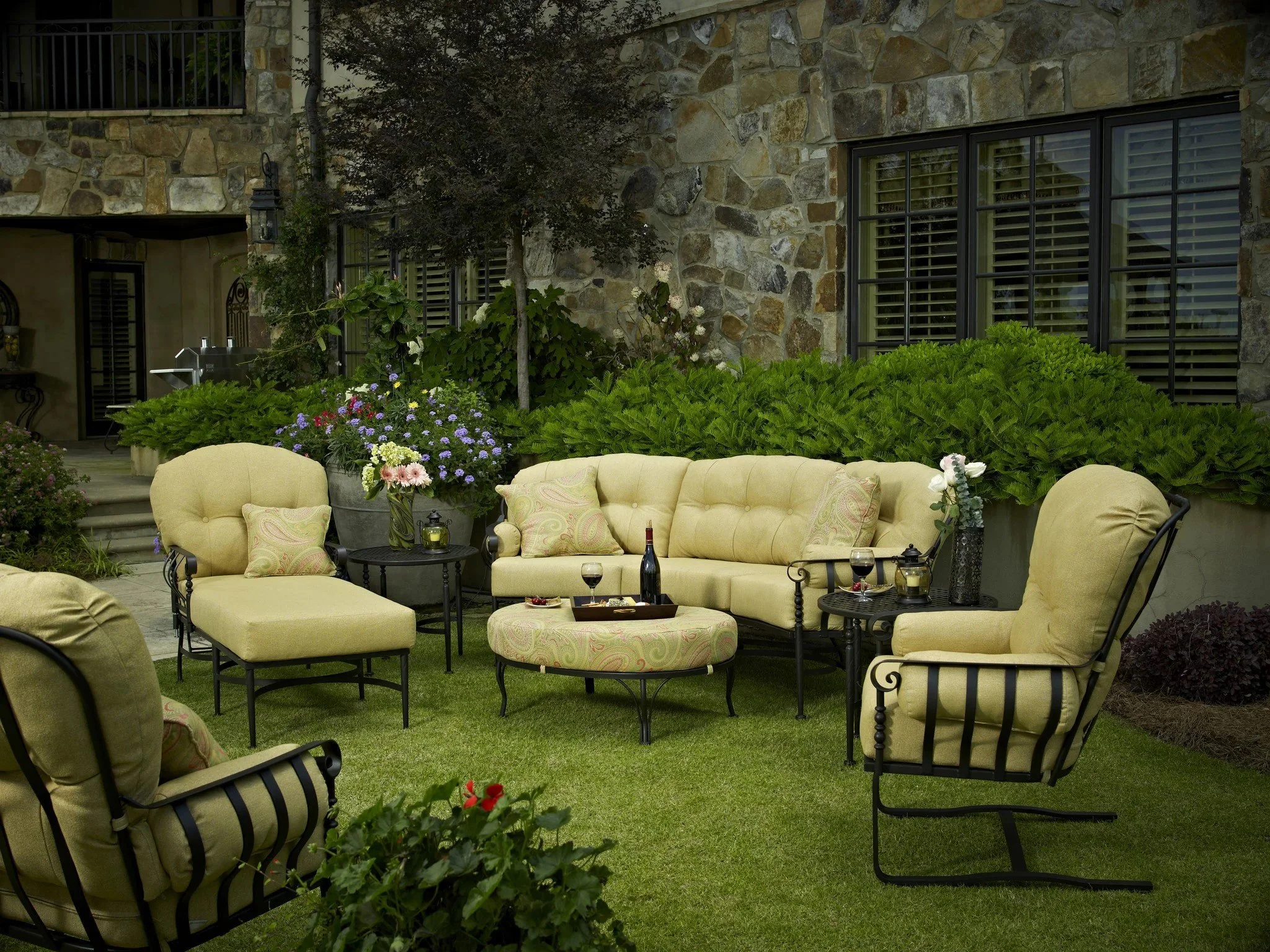  seven piece lounge set with yellow cushions on lawn in front of bushes and stone building