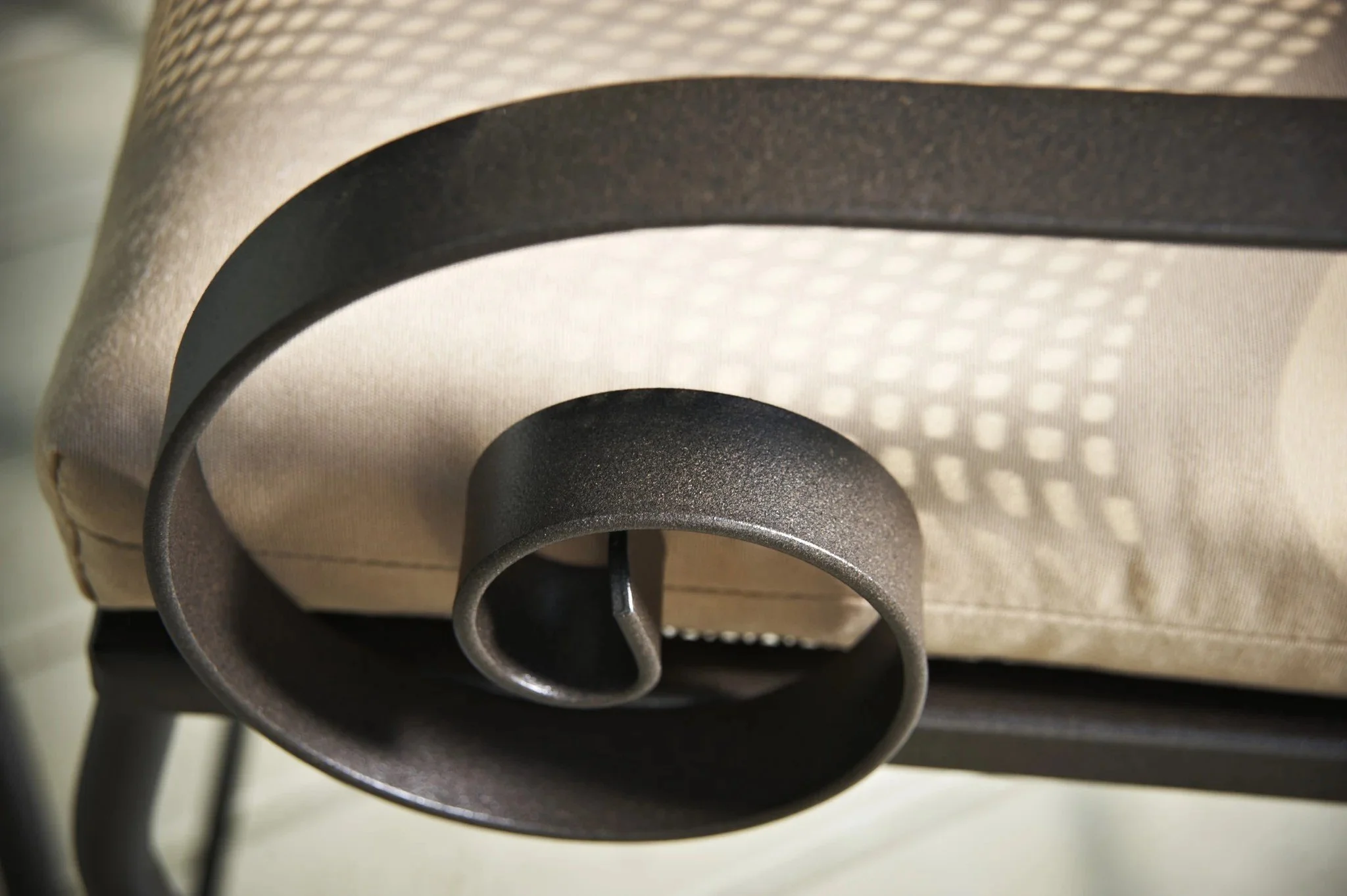 close up of spiraled wrought iron chair arm with white cushion