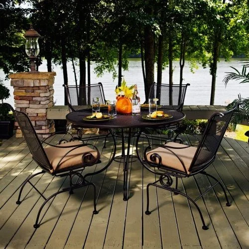 5 piece wrought iron dining set with brown cushions on deck next to lake
