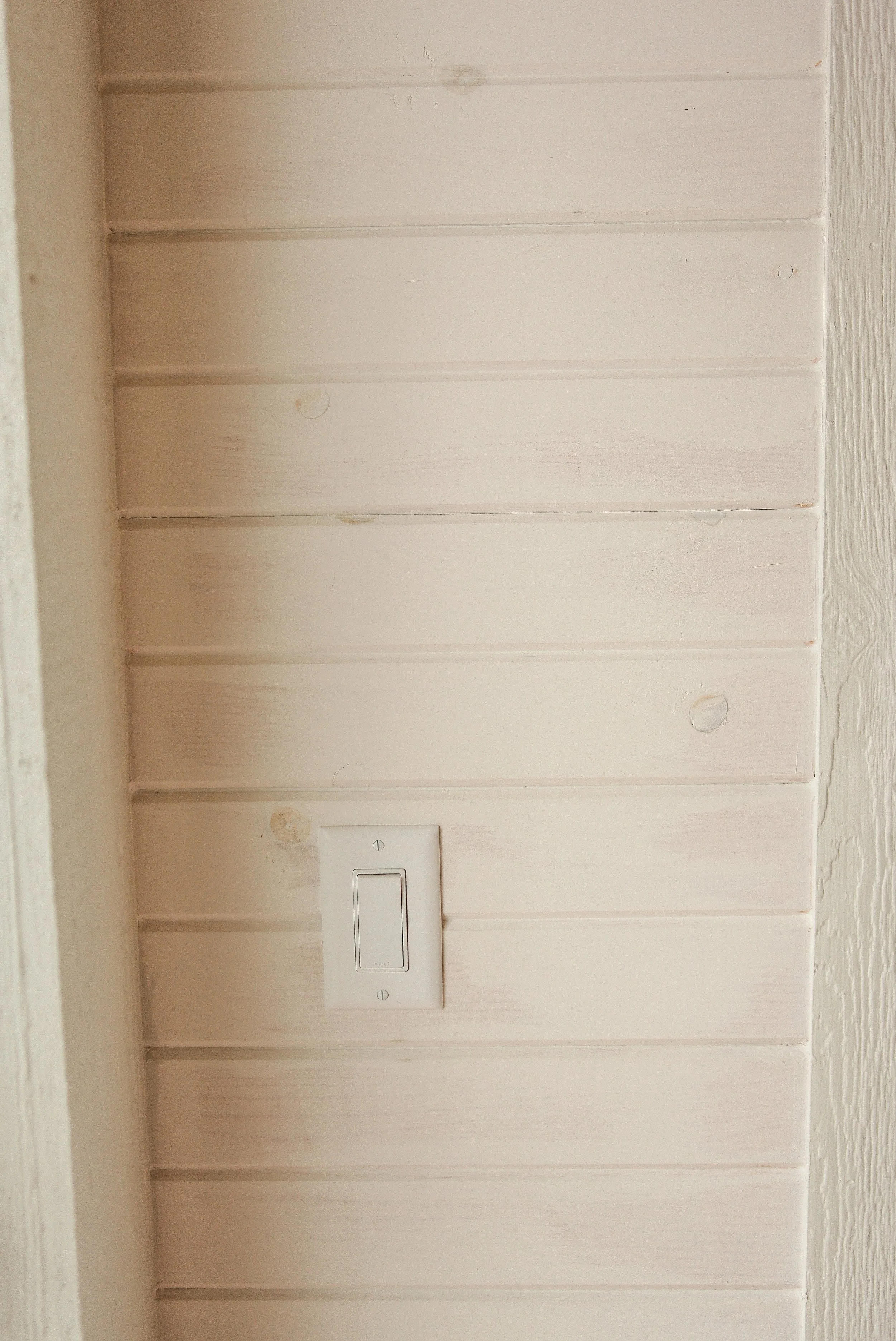 Close-up of a light switch on a white wooden wall.