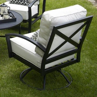 wrought iron swivel rocker with white cushion next to lounge chair and coffee table on grass