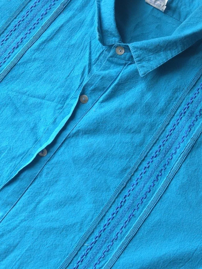 A men's blue collar shirt with thin pleating and embroidery in the sides of the shirt.