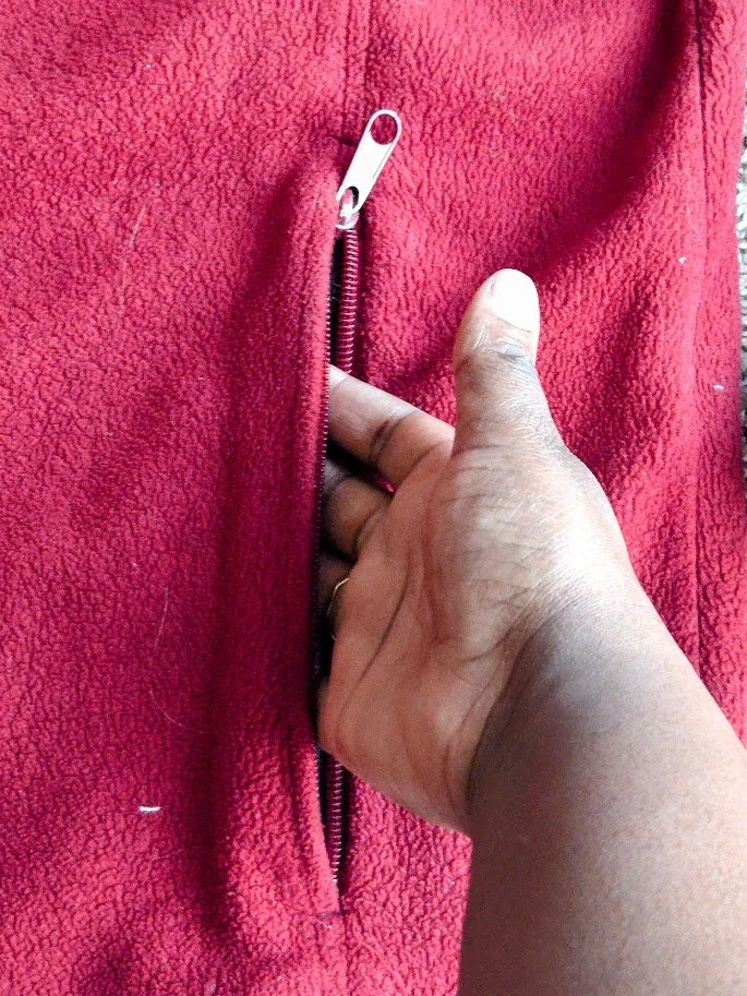 A hand reaching for the inside of a red fleece sweater jacket.
