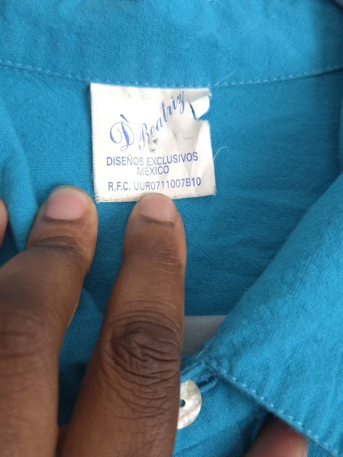 A detailed shot of a men's linen shirt label with letters and numbers.