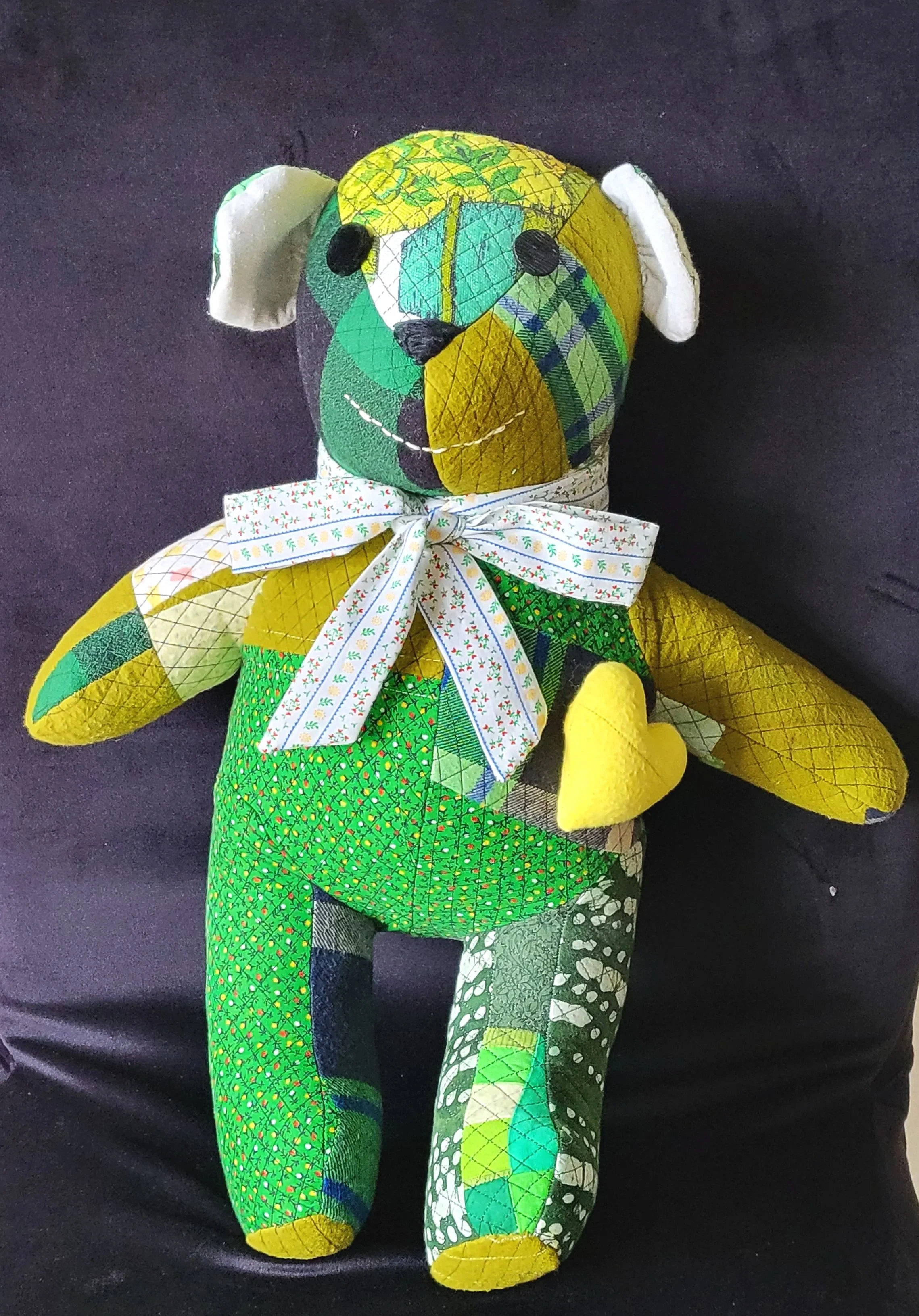 A green patchwork stuffed bear on a dark background.