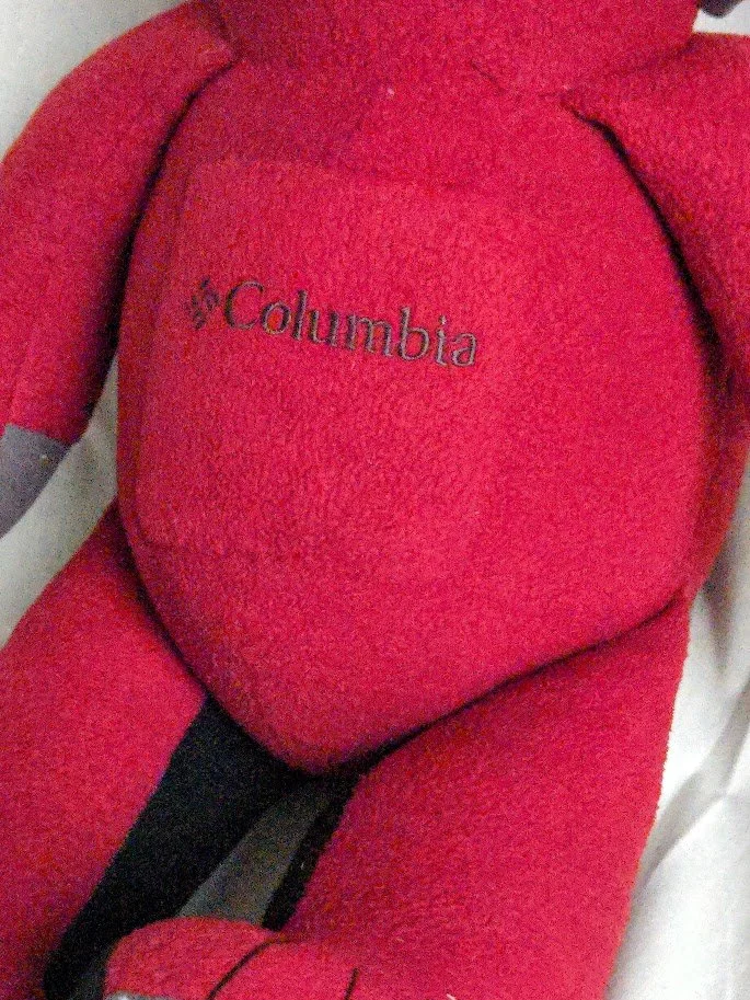Close-up of the Columbia logo embroidered on the front of a red stuffed teddy bear.