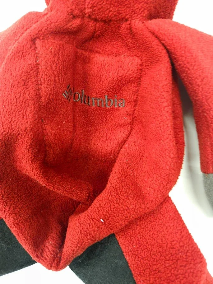 Close-up of the Columbia logo with handstitching on the front of a red fleece stuffed teddy bear.
