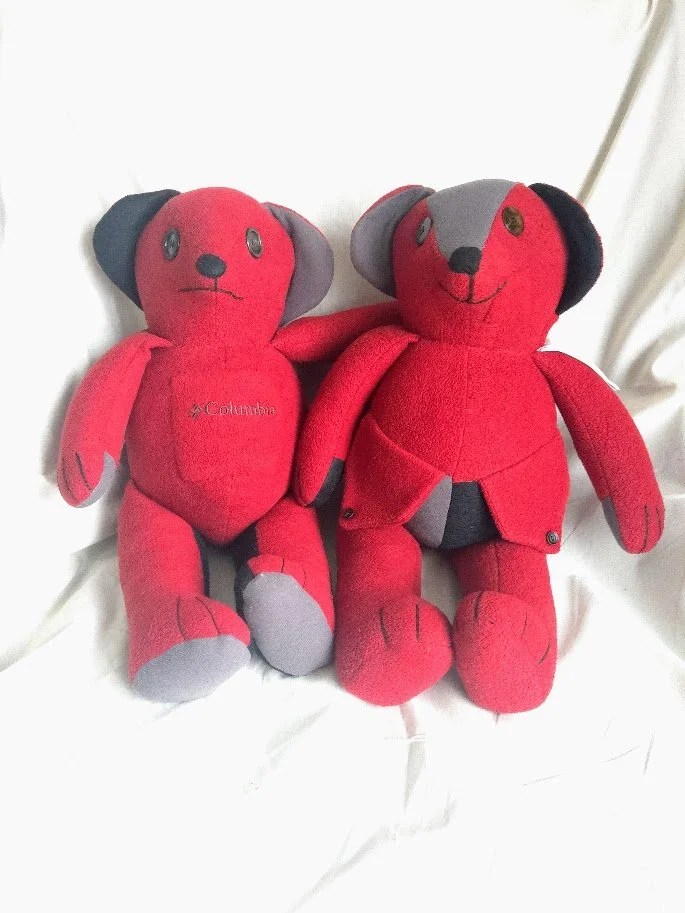 Two red and black upcycled fleece stuffed bears together on a neutral background.