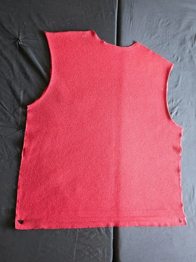 A piece of a red fleece jacket laying flat on a neutral background.