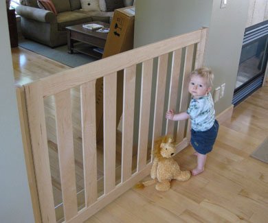 Baby standing by room divider gate by Gatekeepers